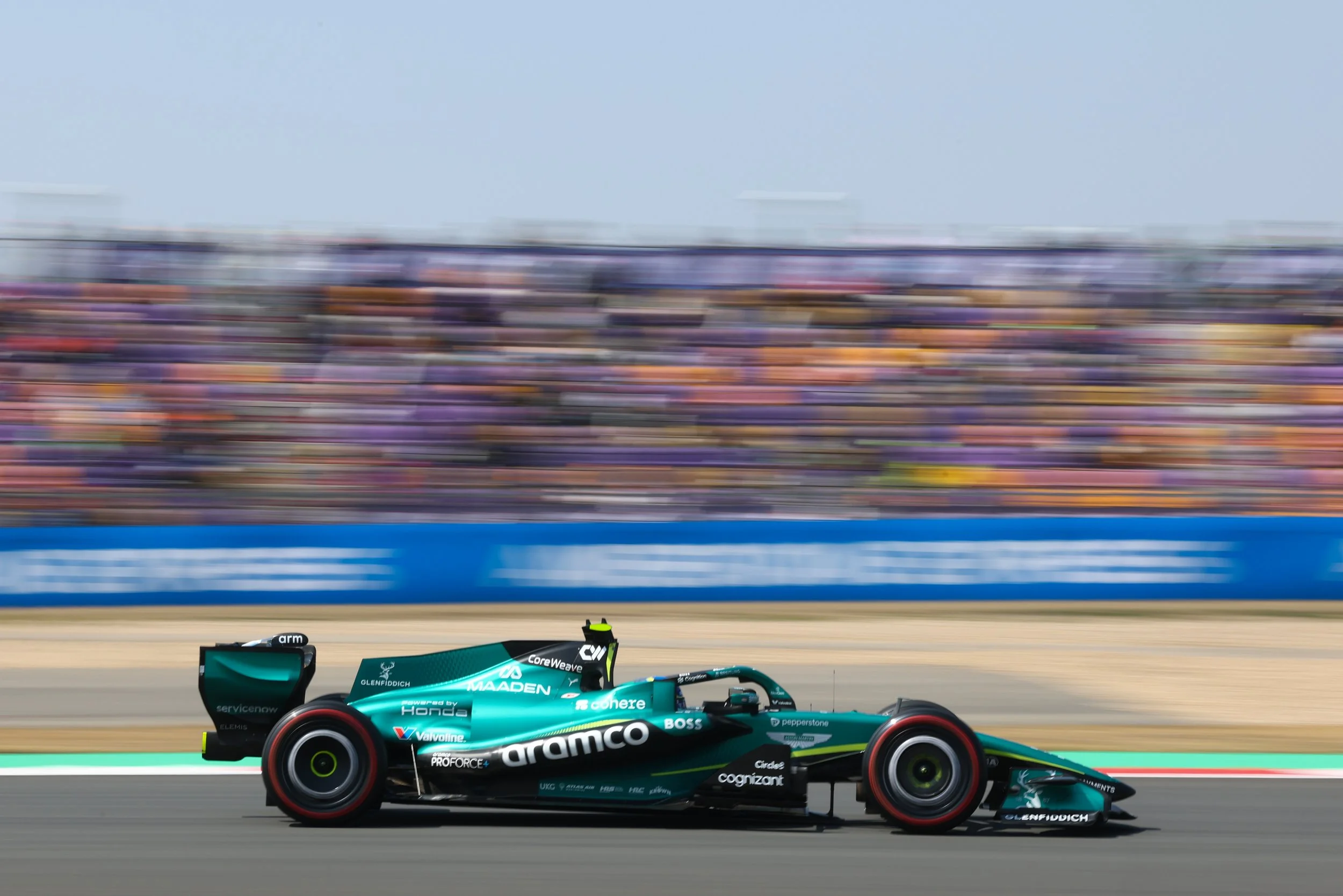 A Formula 1 race car speeding on the track, with a blurred background of spectators and grandstands.