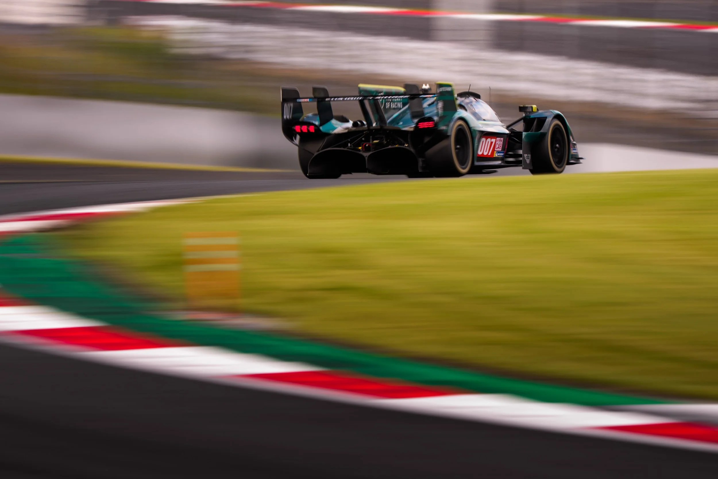 A race car on a track during a race, with a blurred background indicating high speed.