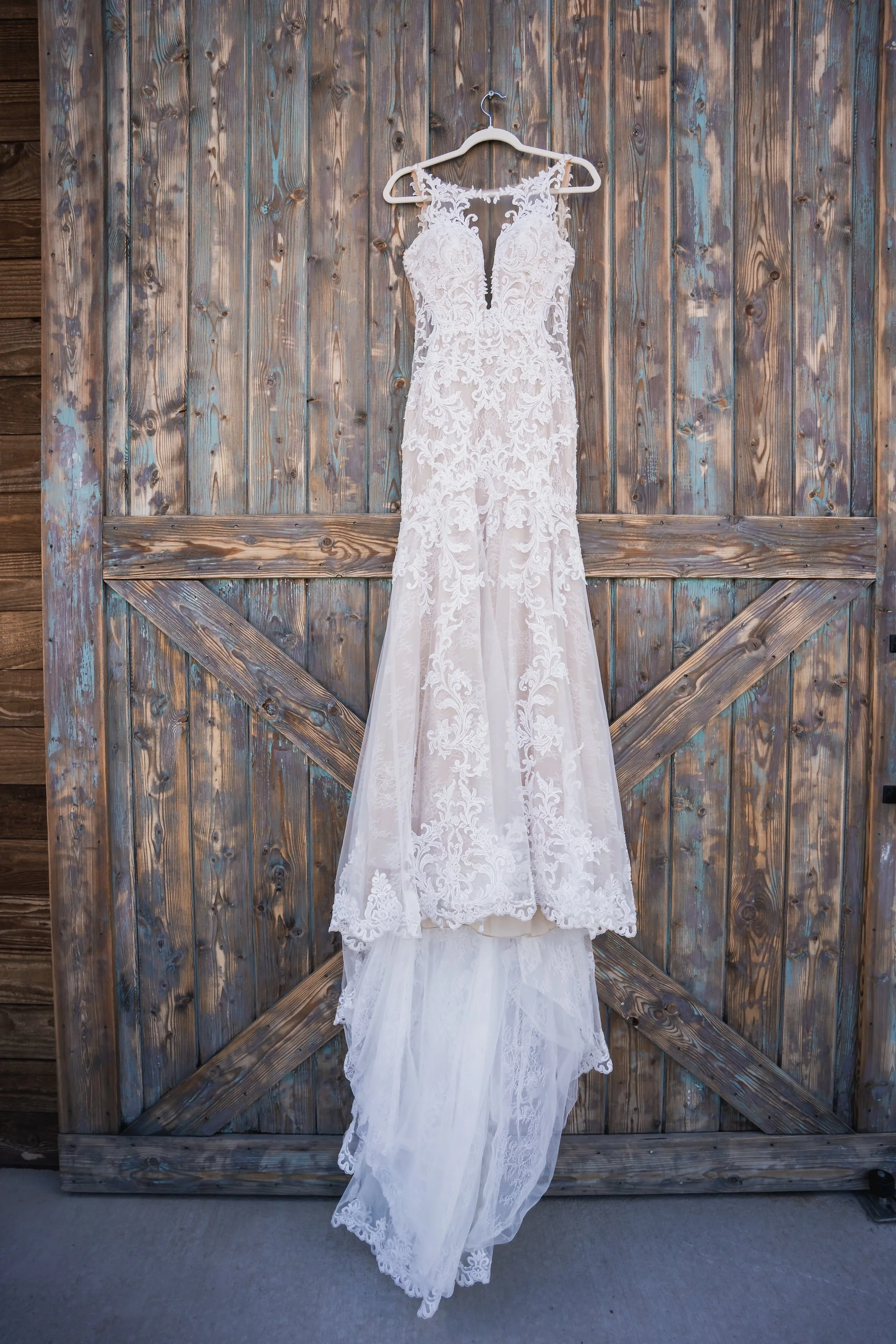 Lace wedding dress hanging on rustic wood door