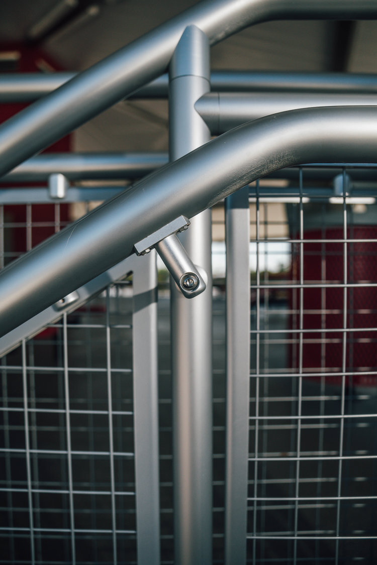 Close-up of metallic handrails and wire mesh structure, possibly a stair railing or barrier.