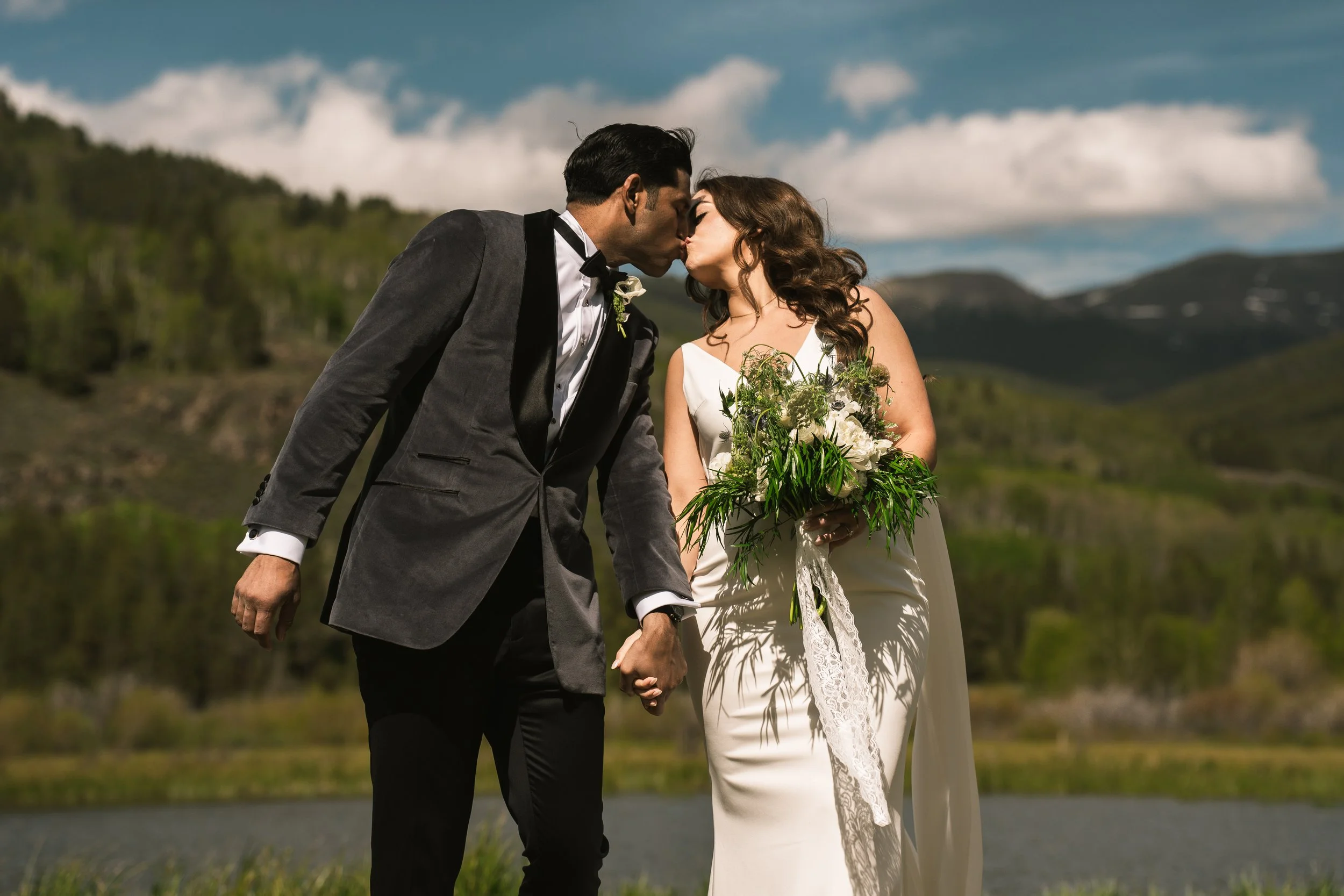 Bride and groom kissing outdoors in mountain landscape