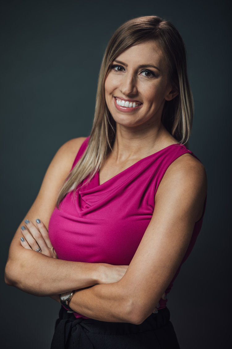 Woman in a pink top smiling with arms crossed