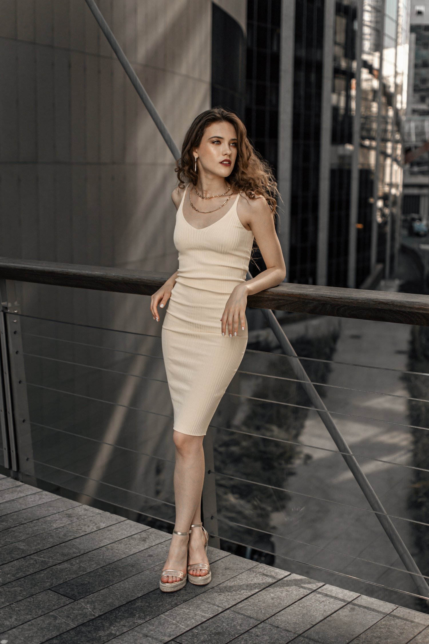 Portrait of a woman in a beige dress against an urban backdrop