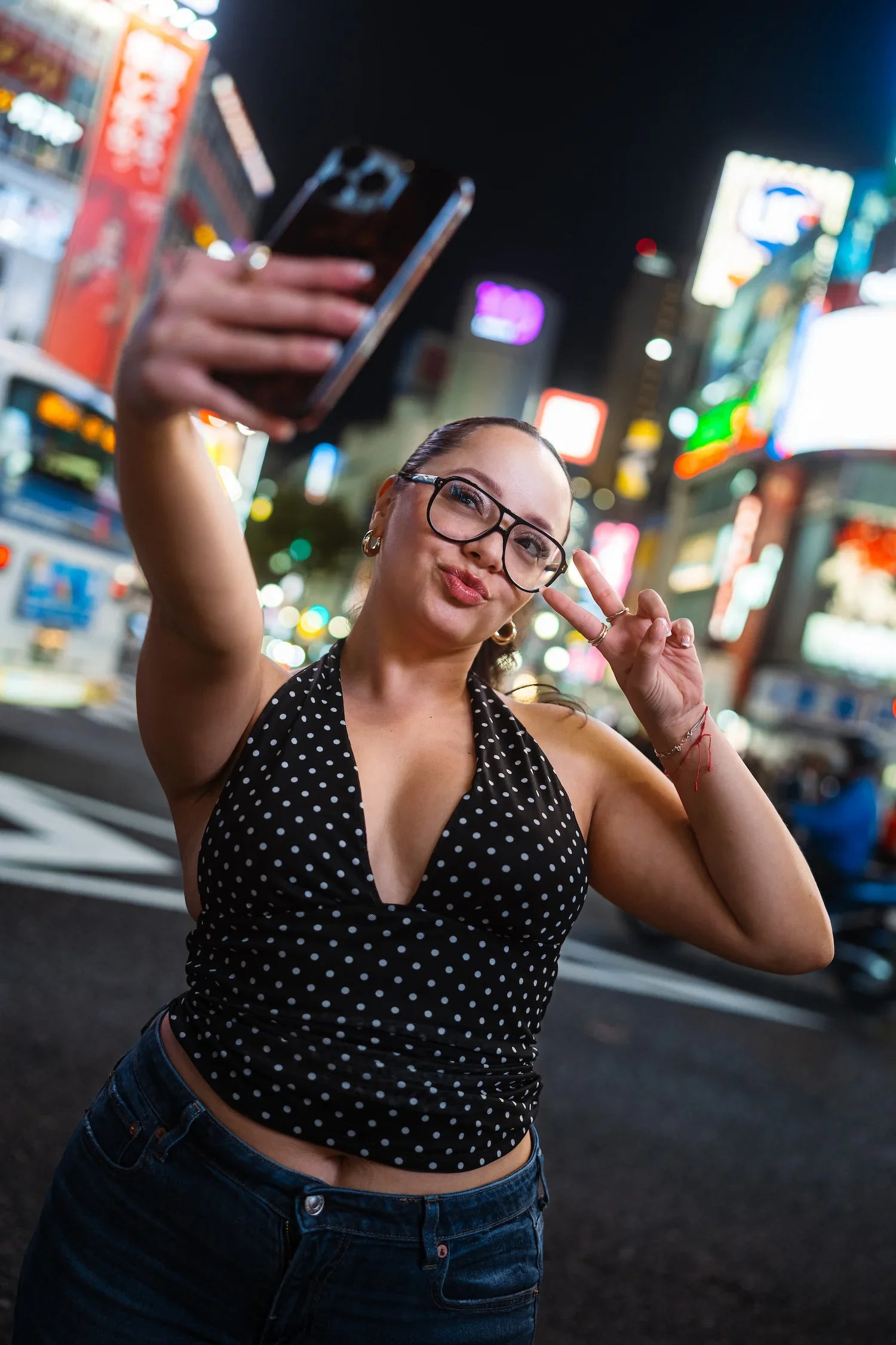 Woman posing playfully among the neon lights of Shibuya during a Tokyo street style portrait session