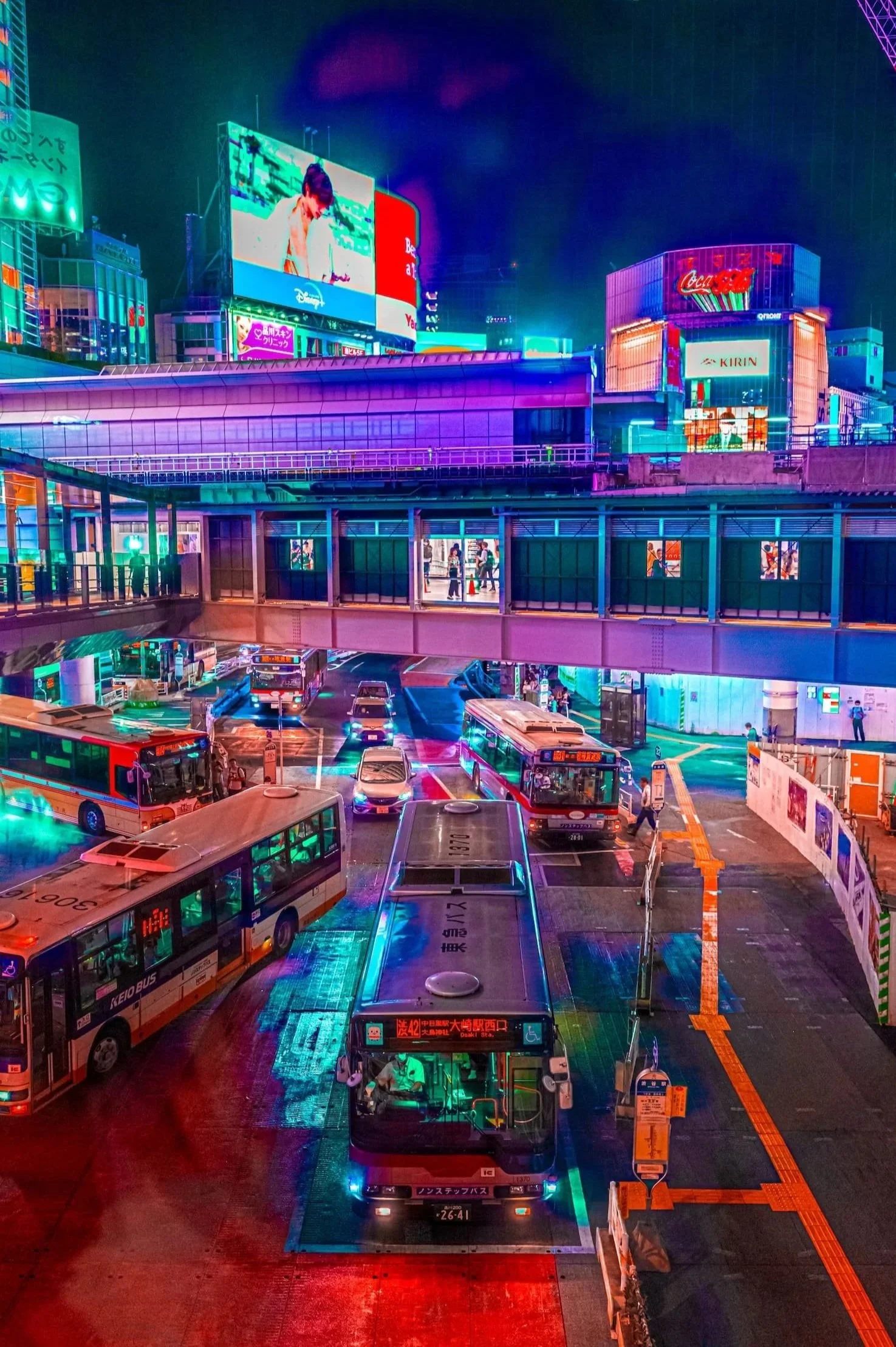 A city scene at night with colorful neon lights, including buses, billboards, and a covered walkway.