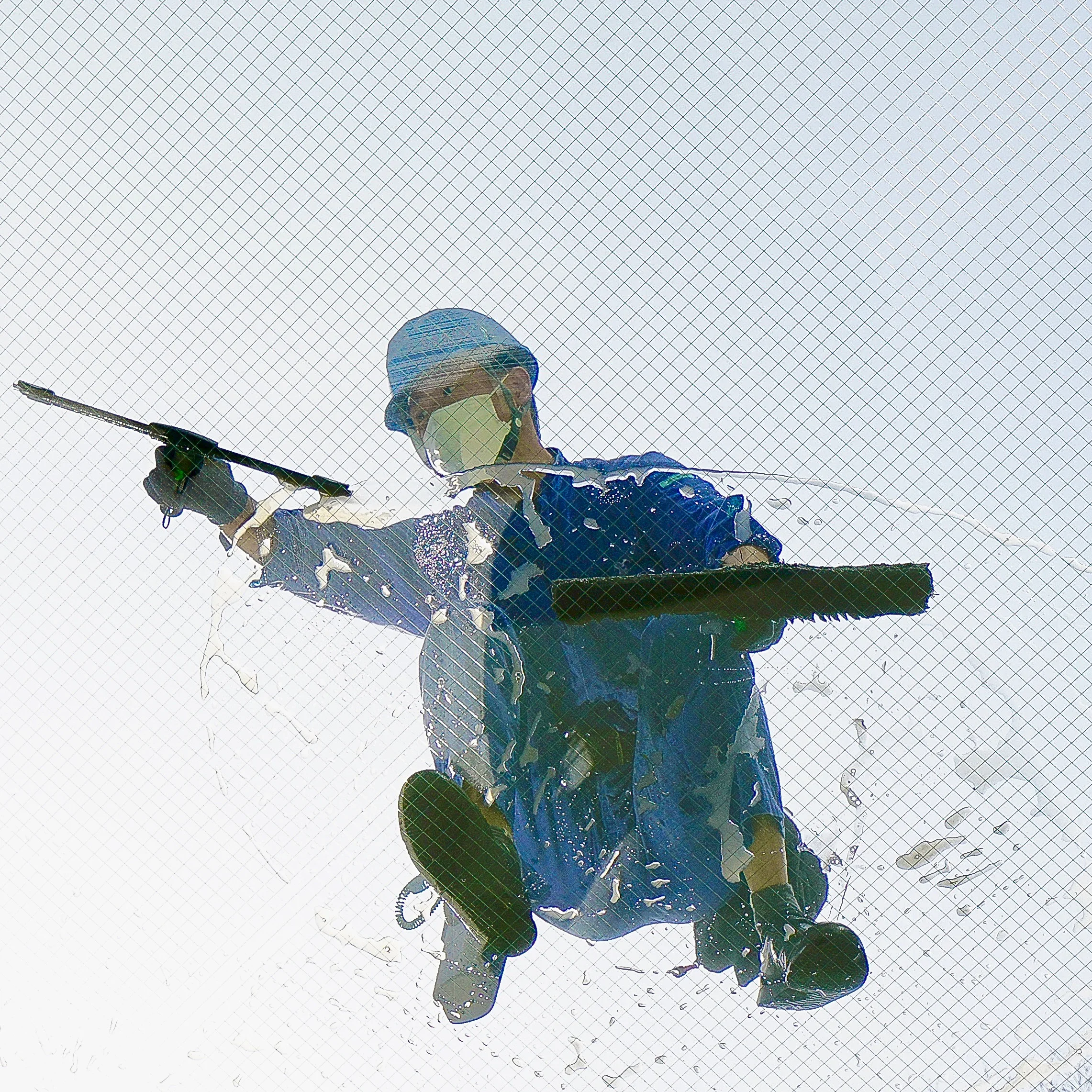 A person in safety gear holding a flag, seen through a mesh or grid, with the sky in the background.