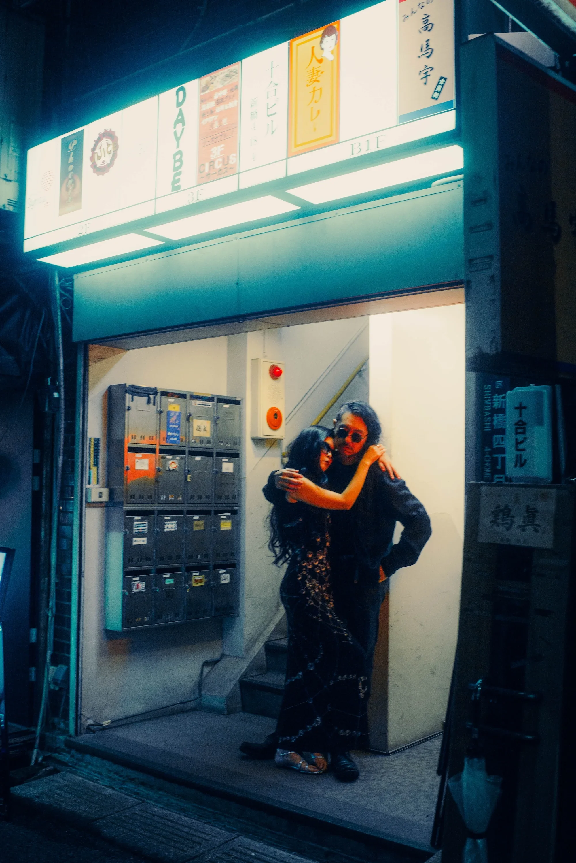 Couple embracing outside a Tokyo building during an atmospheric night photoshoot