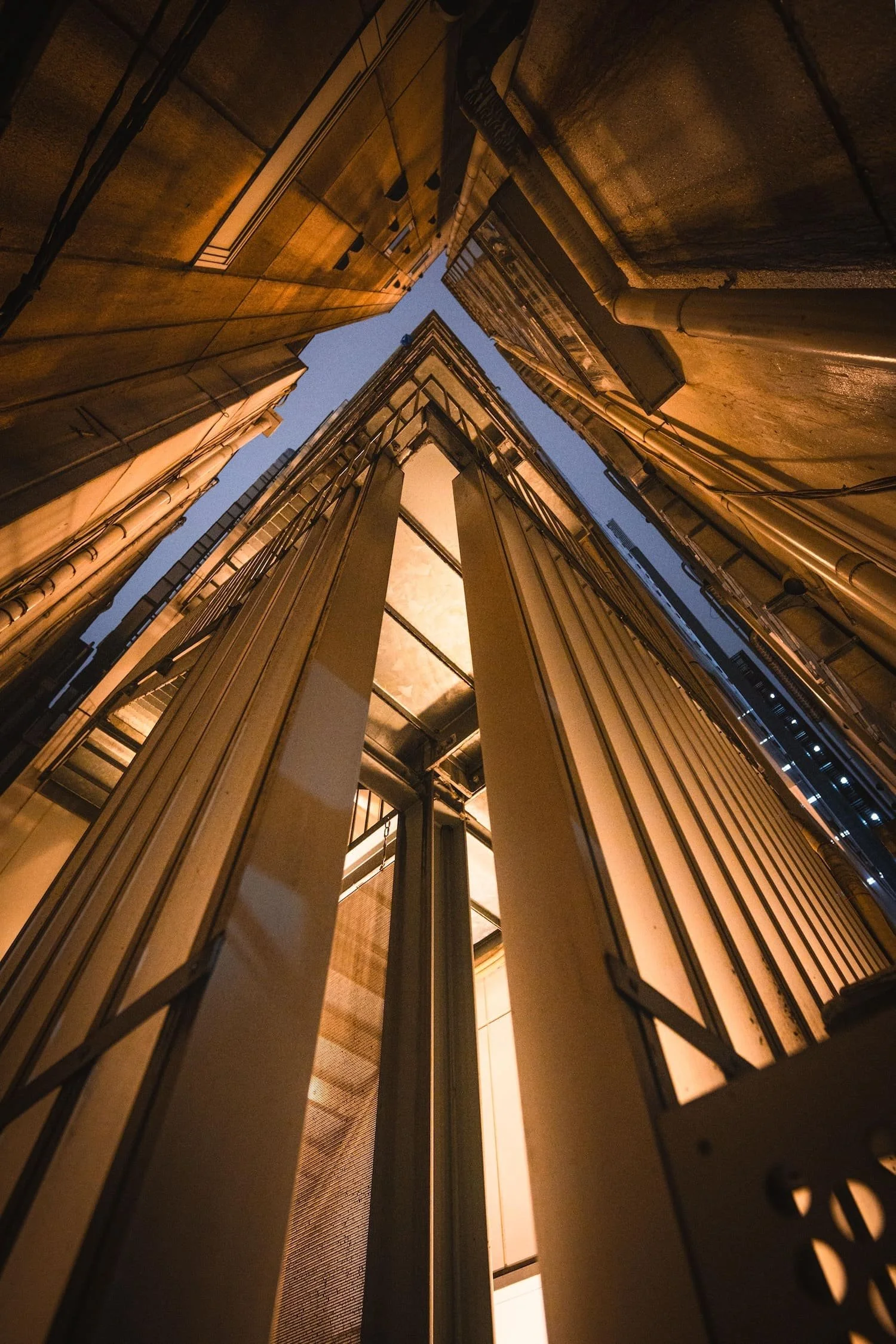 Low-angle view of tall buildings at night, looking up between the narrow spaces.