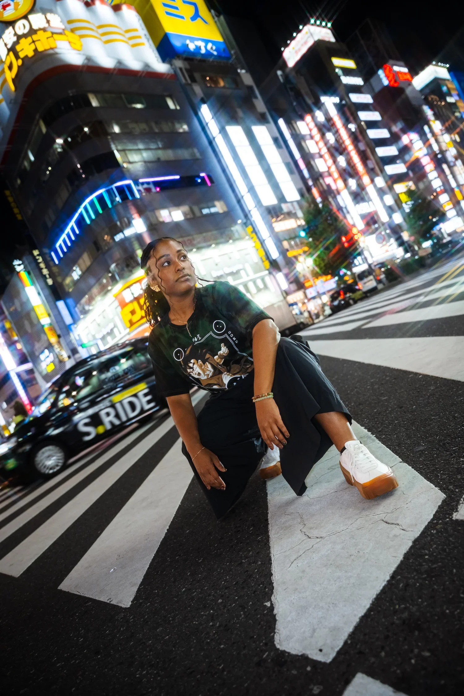 Woman posing beneath the city lights of Shibuya during a Tokyo street style photoshoot