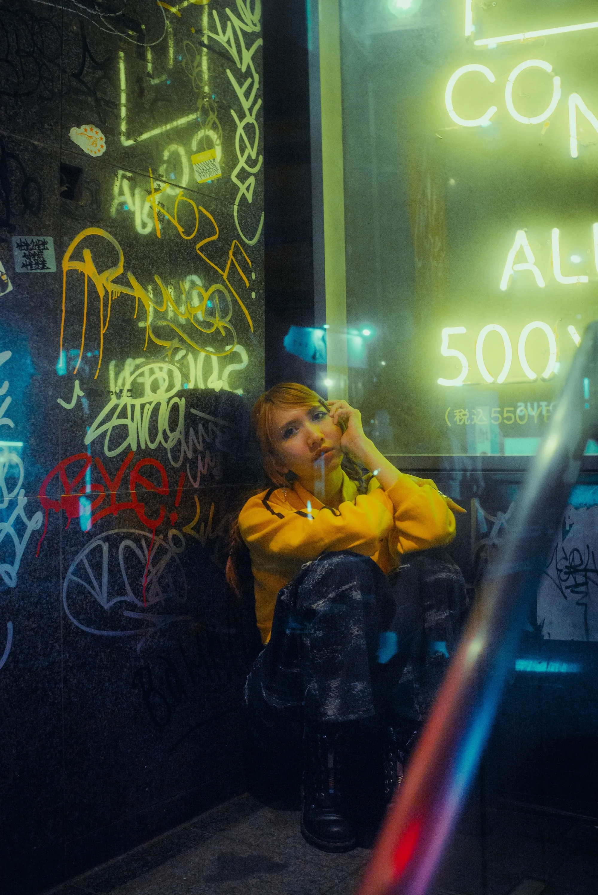 Atmospheric night portrait against graffiti and glowing Tokyo storefront lights