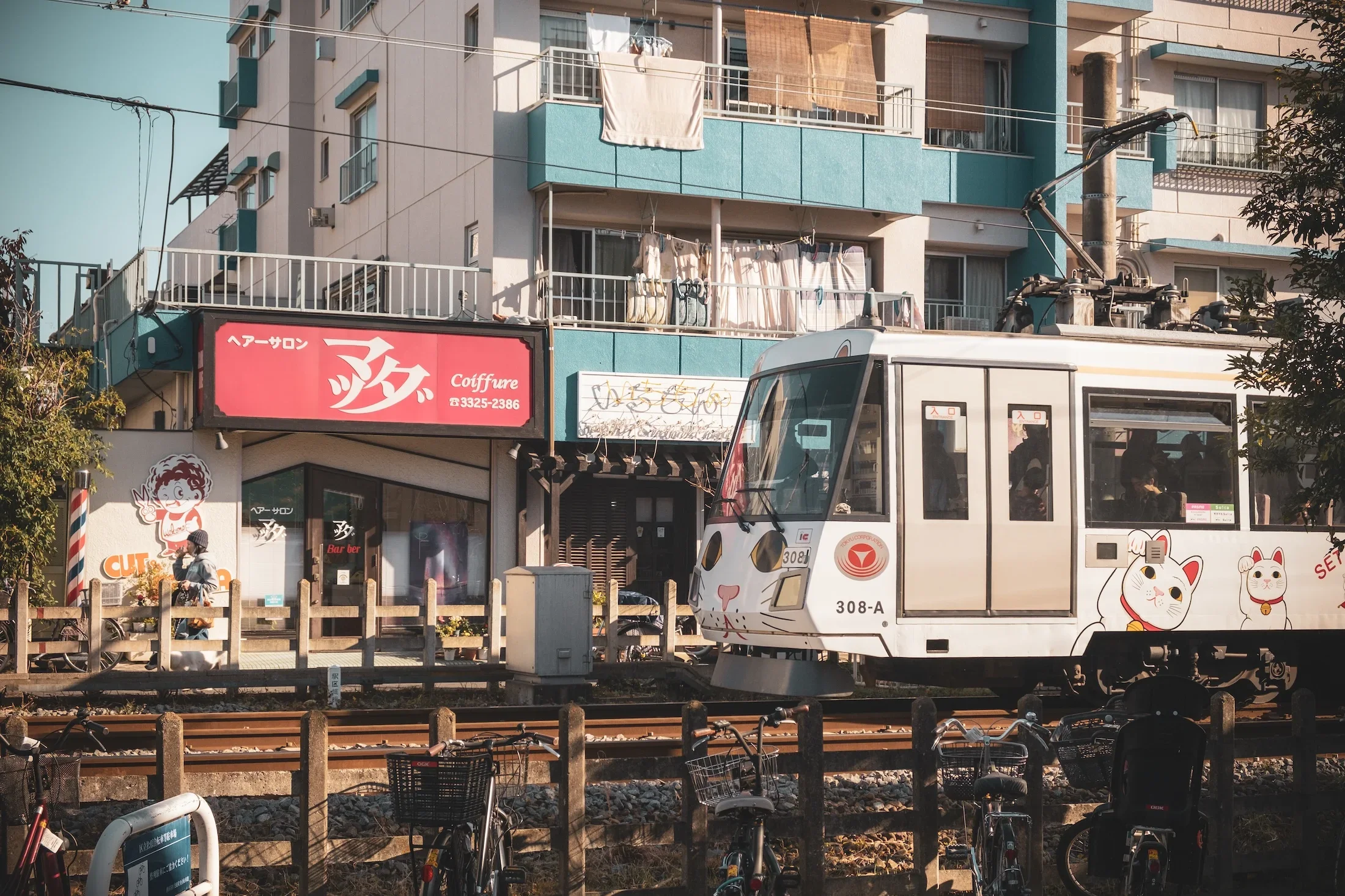 A city scene with a tram, bicycles, and a building with laundry hanging on balconies.