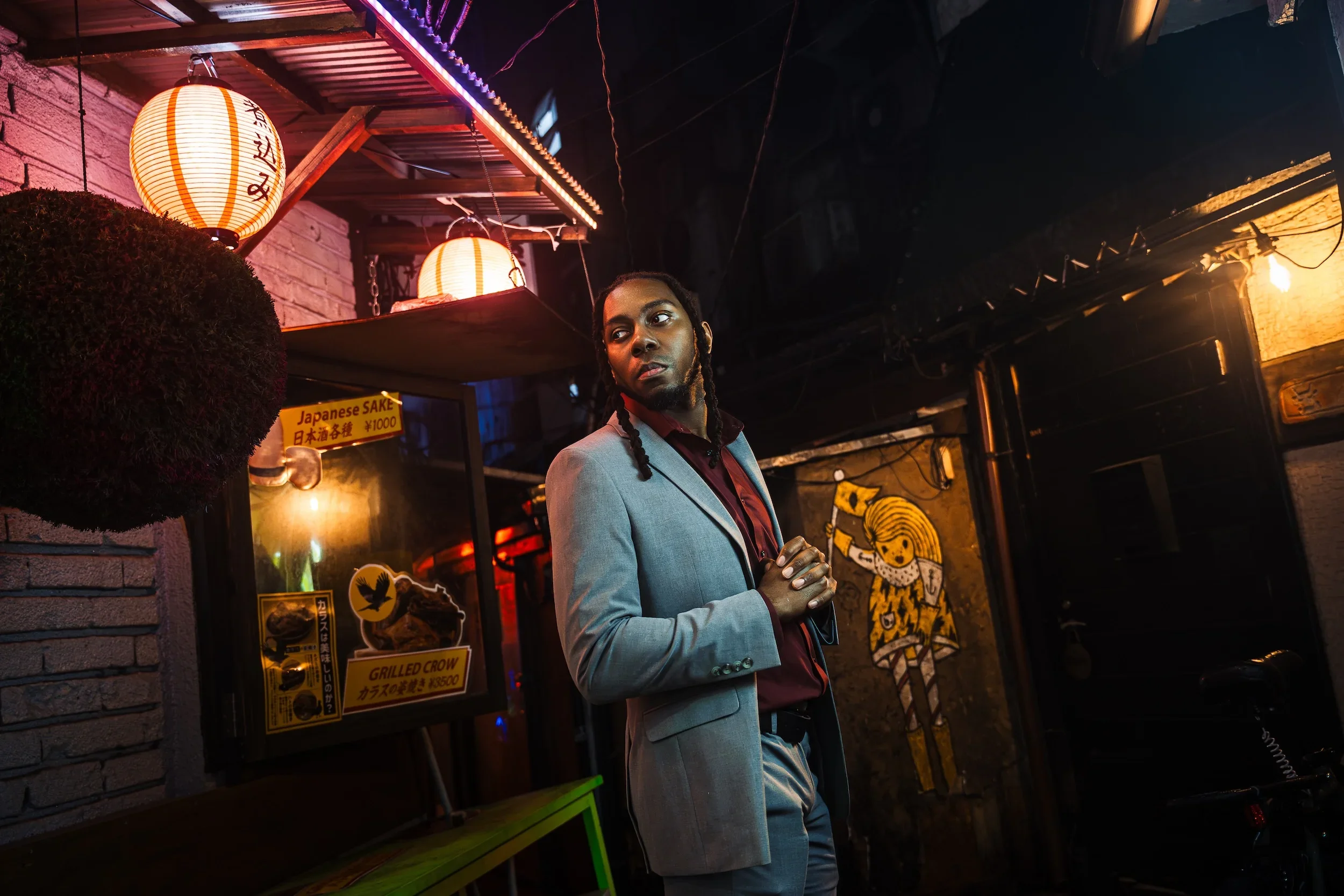 Man in a suit posing in a lantern-lit Tokyo alley during an evening portrait photoshoot