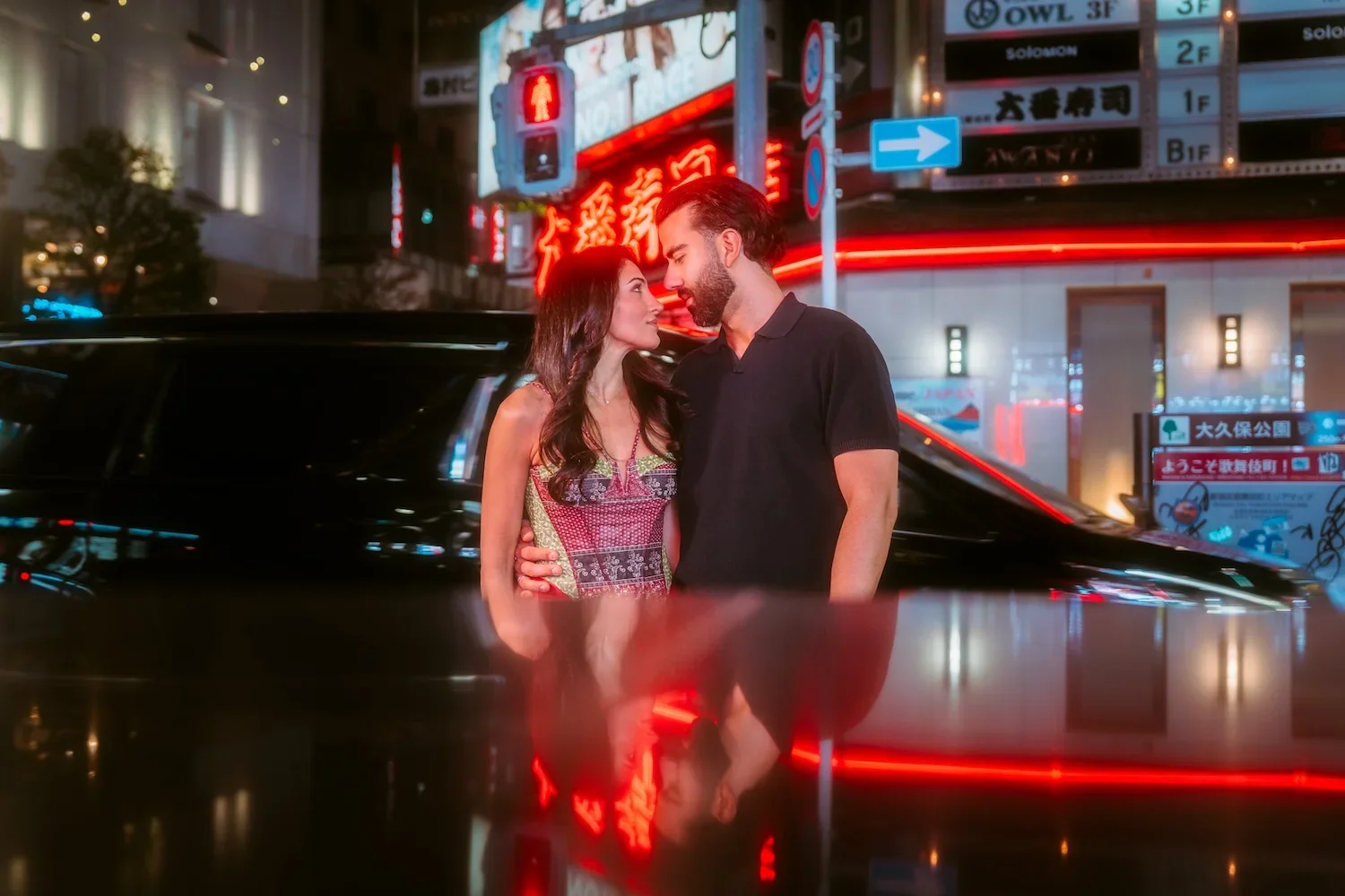 Couple portrait with red neon reflections on a Tokyo street at night in Kabukicho Shinjuku
