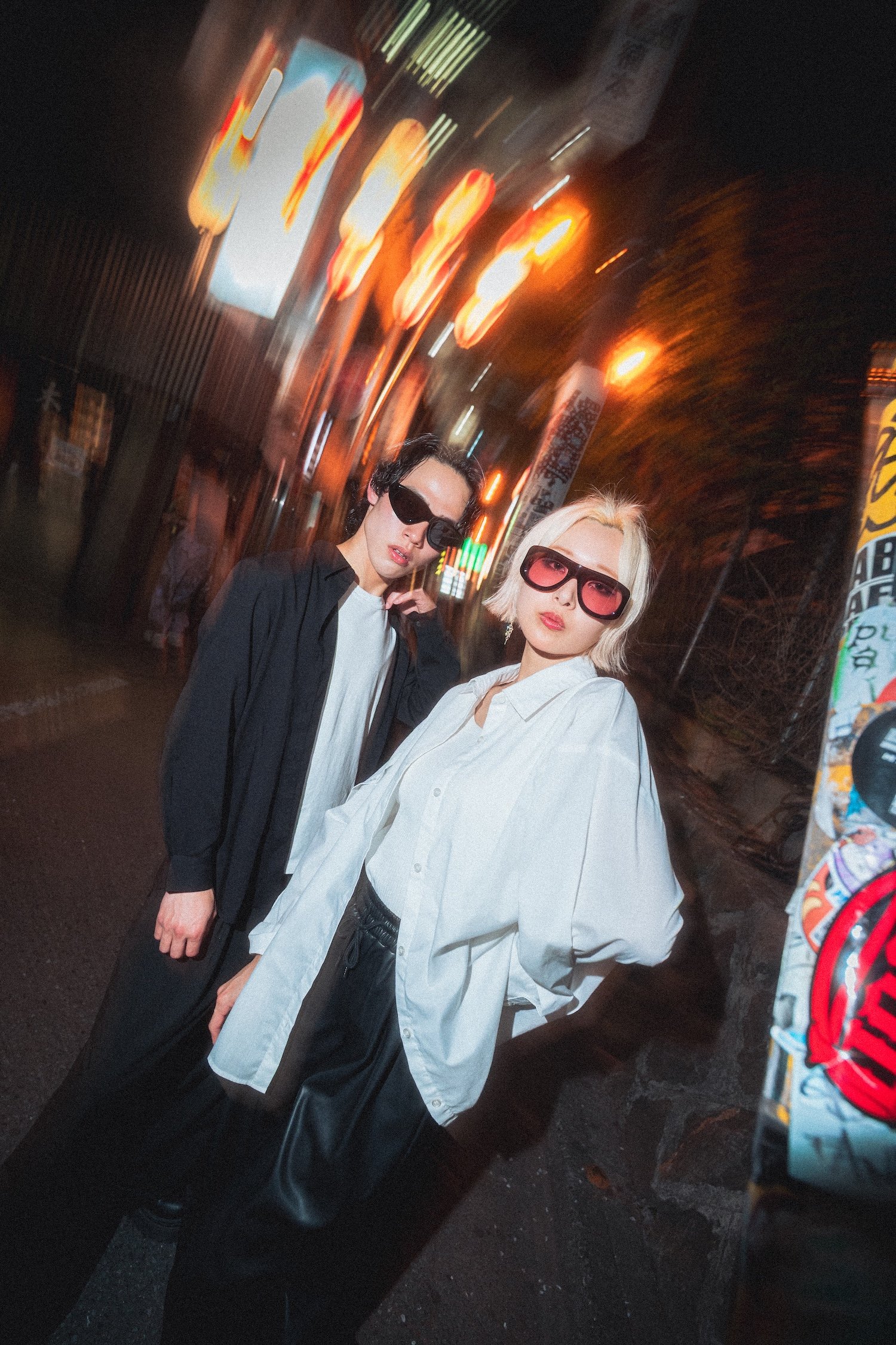 Editorial eyewear photography for Vasuma Eyewear in Tokyo, showing two models wearing fashion sunglasses inside a graffiti-covered stairwell with a modern streetwear aesthetic.