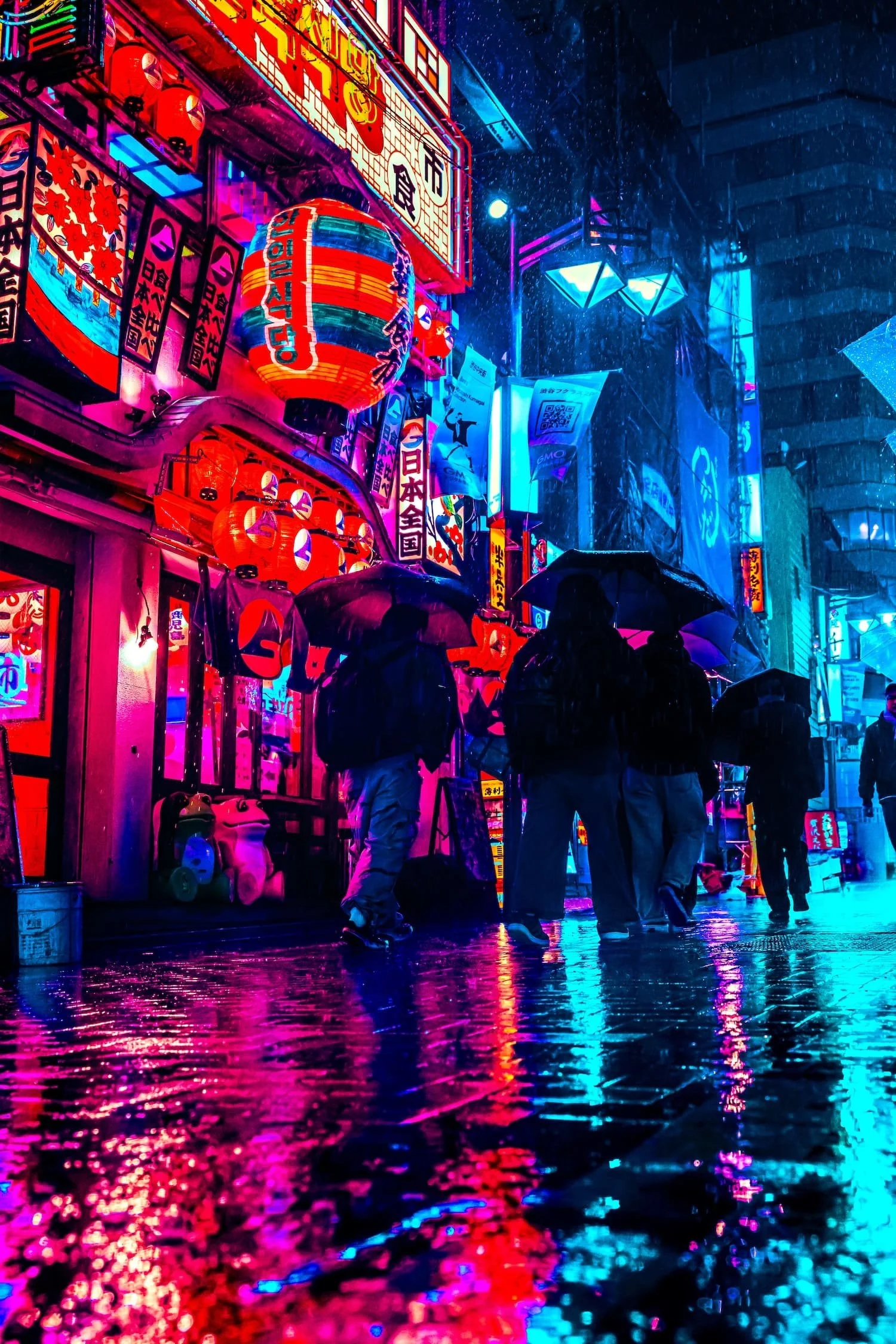 People with umbrellas walking on a rainy street illuminated by colorful neon signs and paper lanterns in an urban area at night.