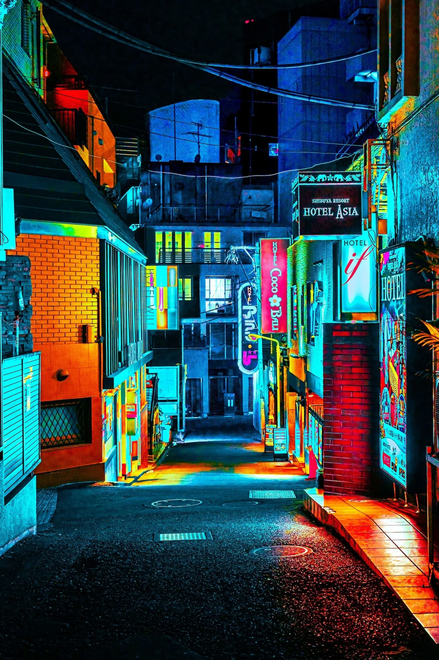 Nighttime street scene illuminated by vibrant neon signs for hotels, with colorful buildings and advertisements in a city alleyway.