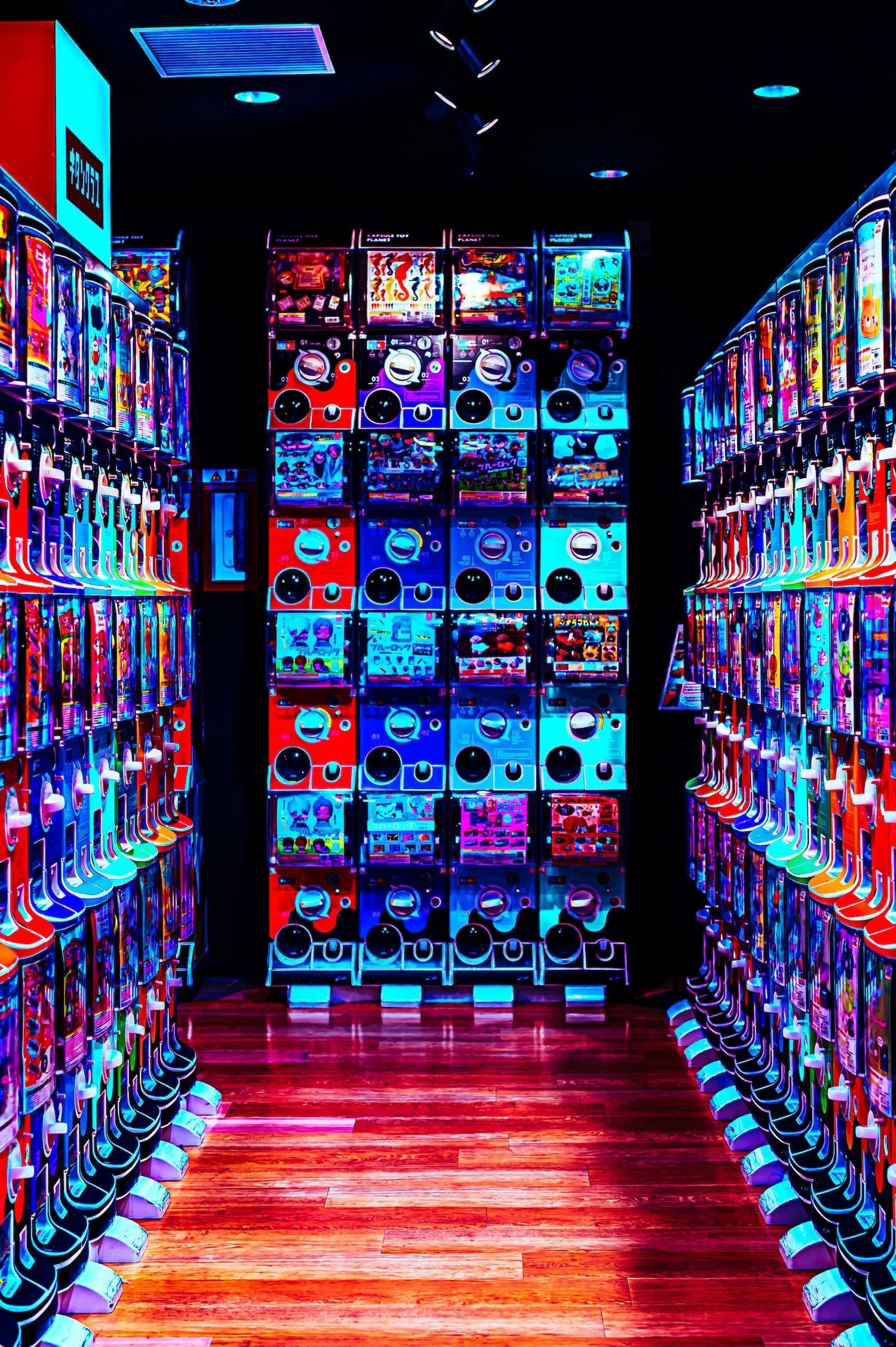 Colorful arcade with brightly lit claw machines filled with toys and prizes, and a wooden floor.