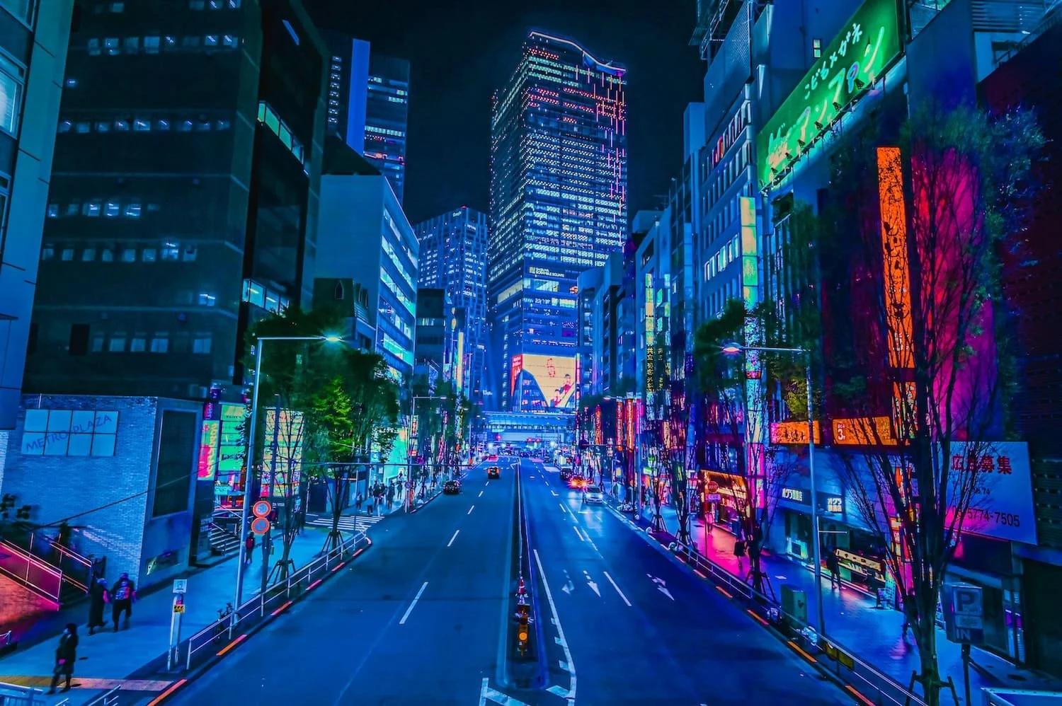 City street at night illuminated with colorful neon lights and tall skyscrapers.