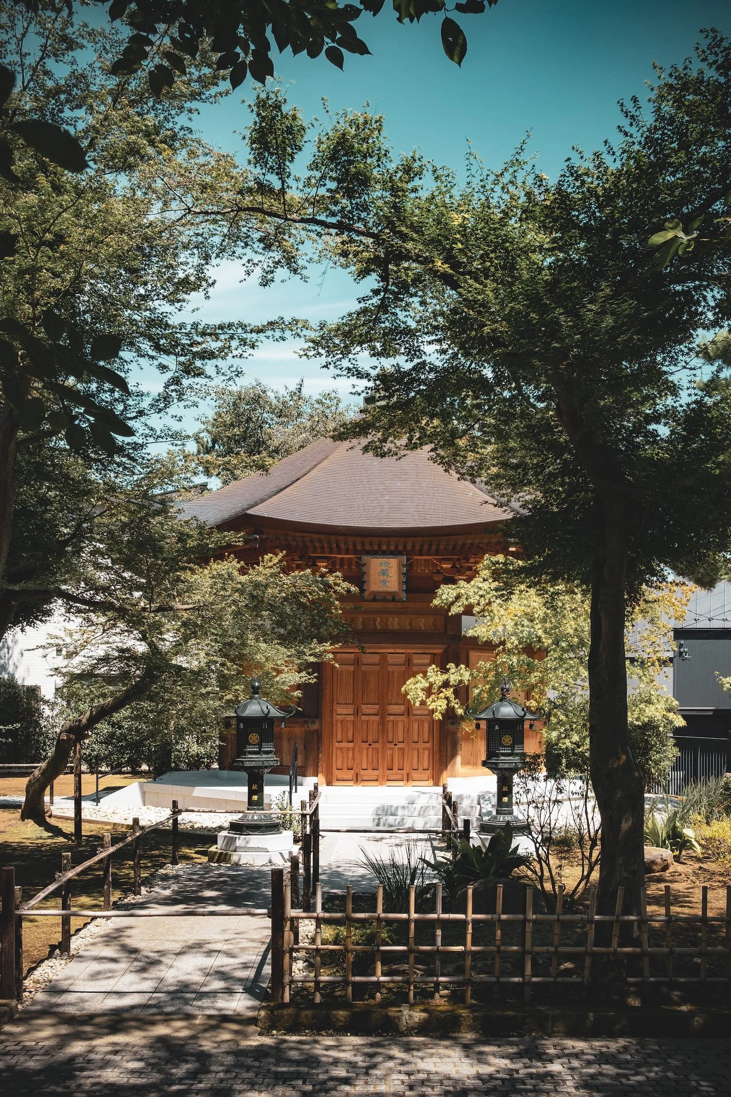 A traditional Japanese wooden shrine surrounded by trees and a small pathway leading to it.
