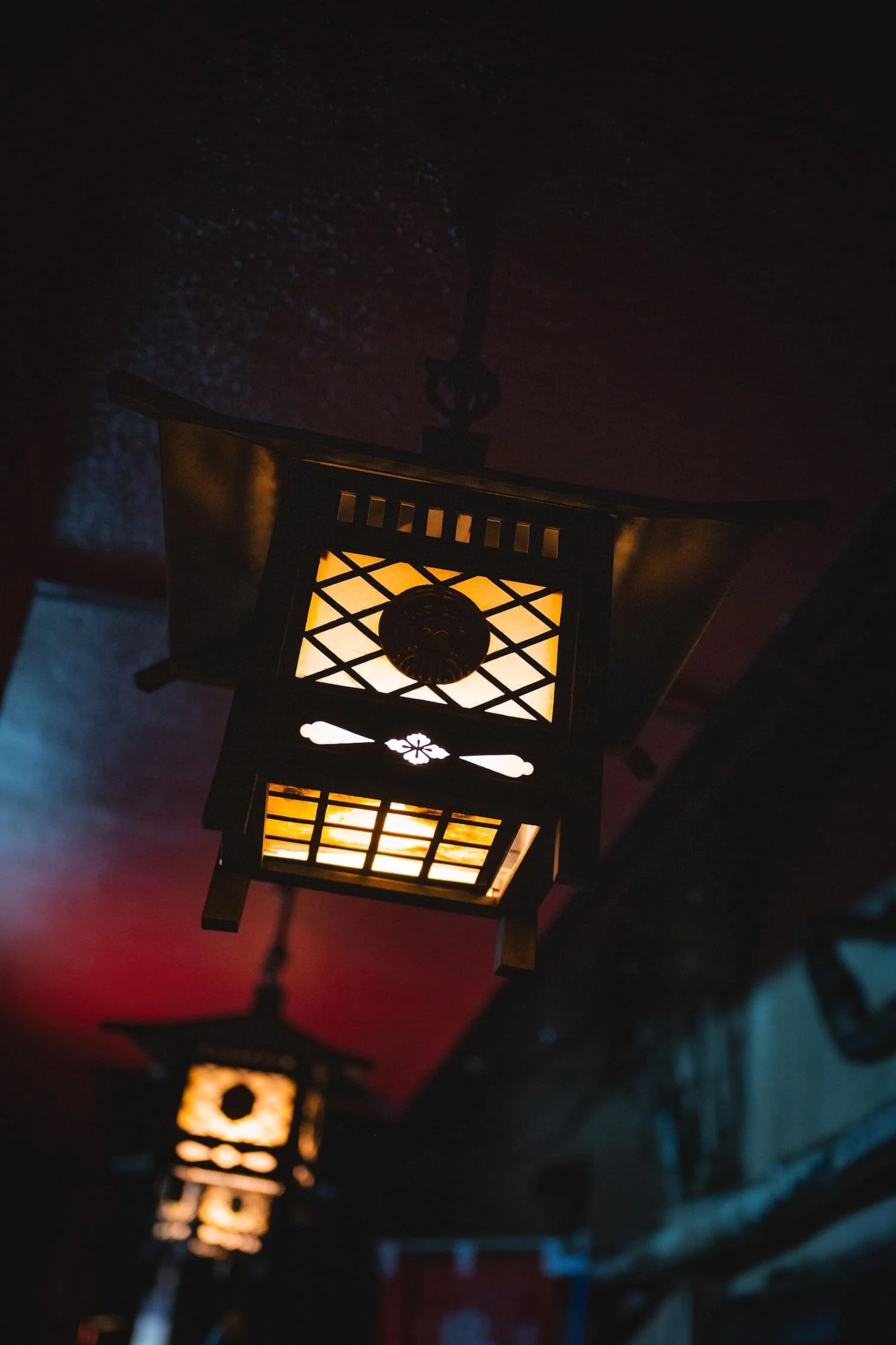 Japanese-style lantern hanging from ceiling in a dimly lit room.