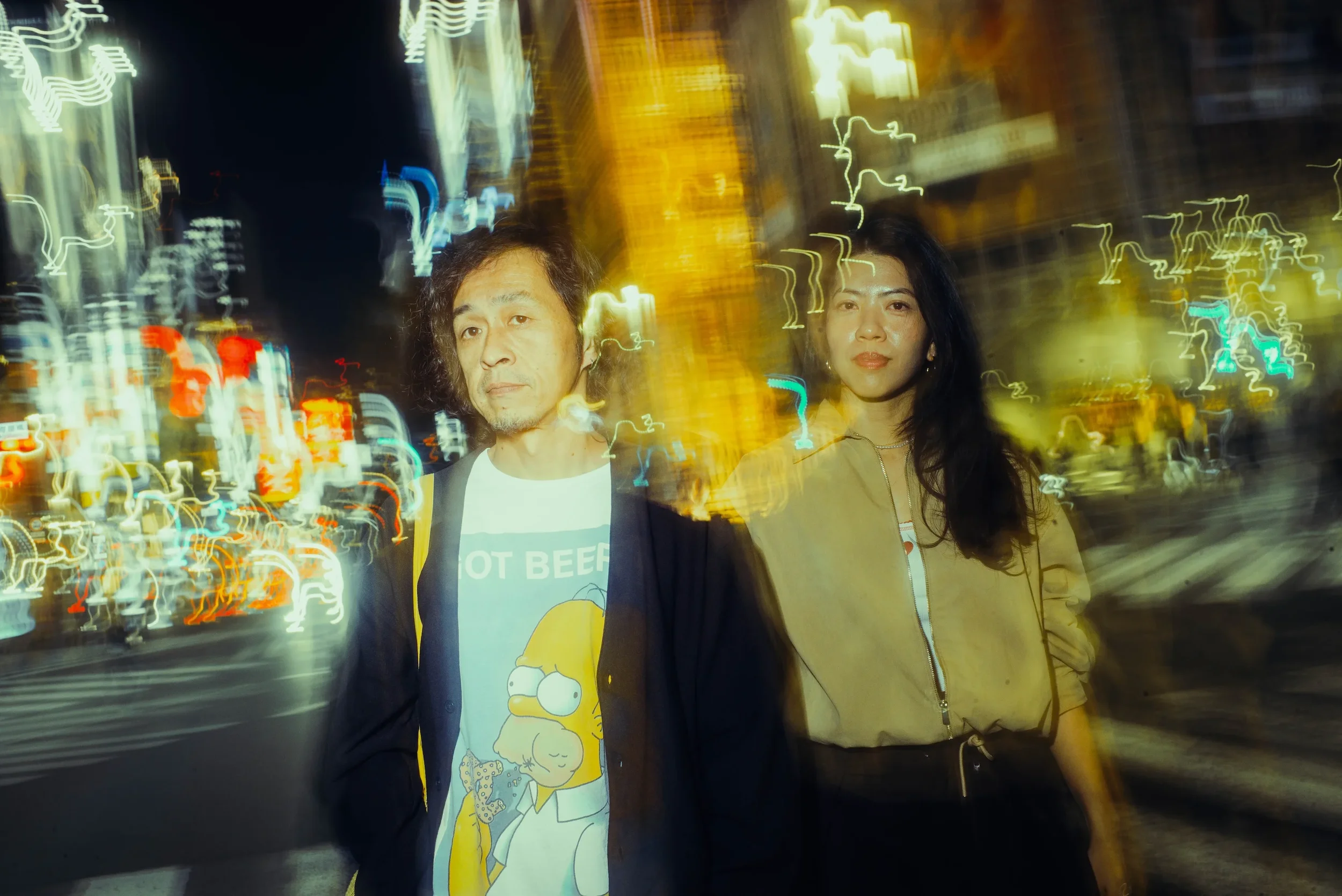 Couple photographed against colorful motion-blurred Tokyo nightlife during an After Dark photoshoot