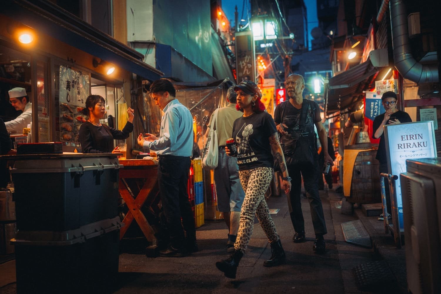 People walking and ordering food at an outdoor night market with colorful lights and Japanese signs. Shot in Nakano by Tokyo street photographer.Deniz Demir during a photography workshop for Tekumi.