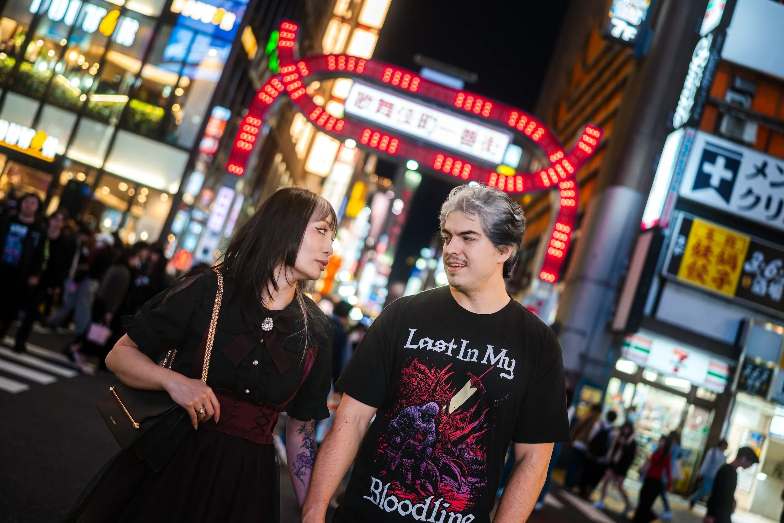Couple walking through neon-lit Shibuya during a Tokyo street style photoshoot