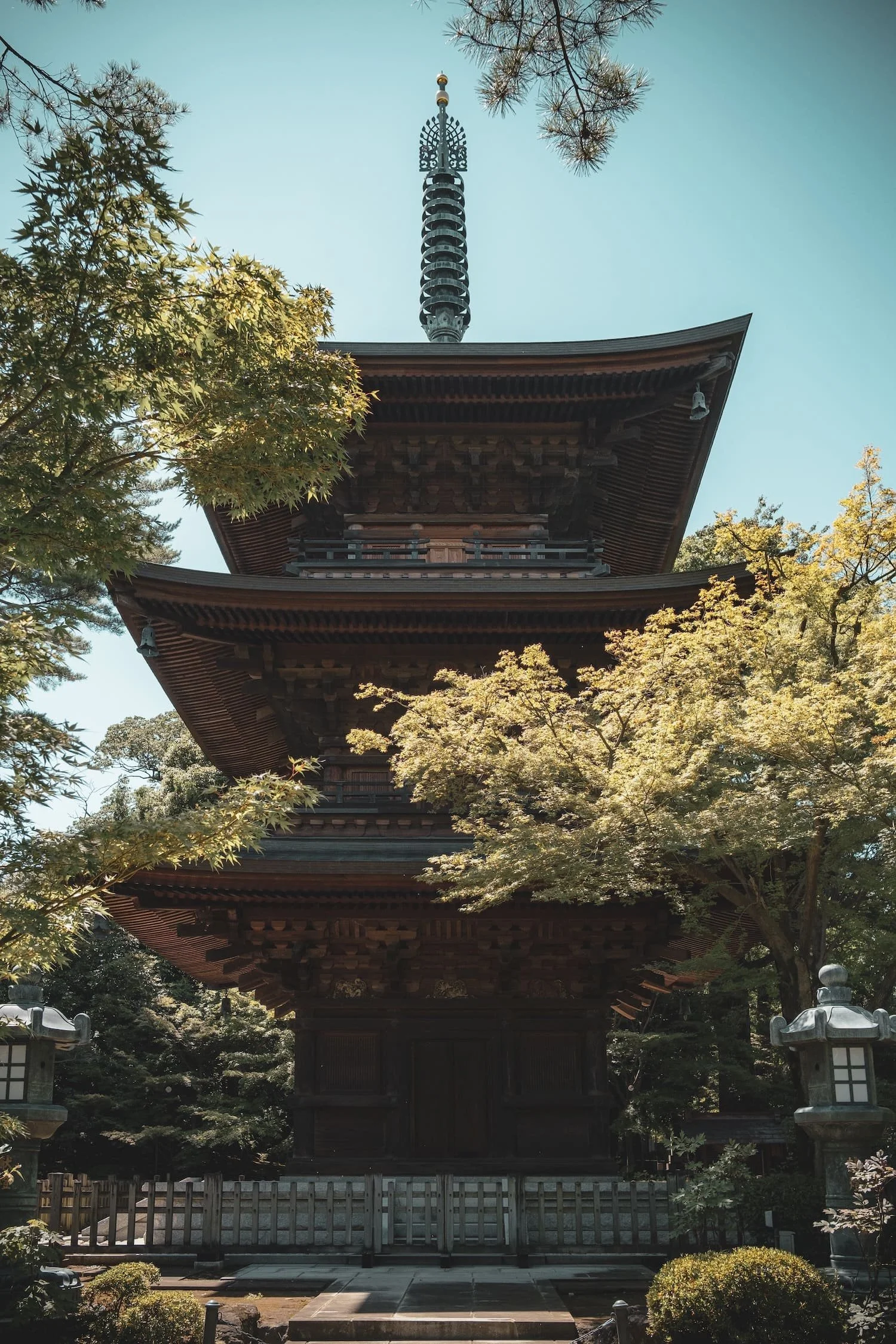 A traditional Japanese pagoda surrounded by trees and stone lanterns.