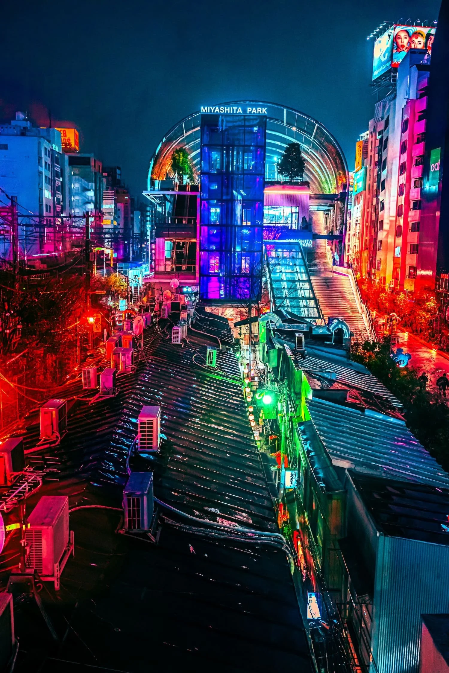 Night scene of Miyashita Park in Tokyo illuminated with colorful neon lights, surrounded by buildings with vibrant signage.