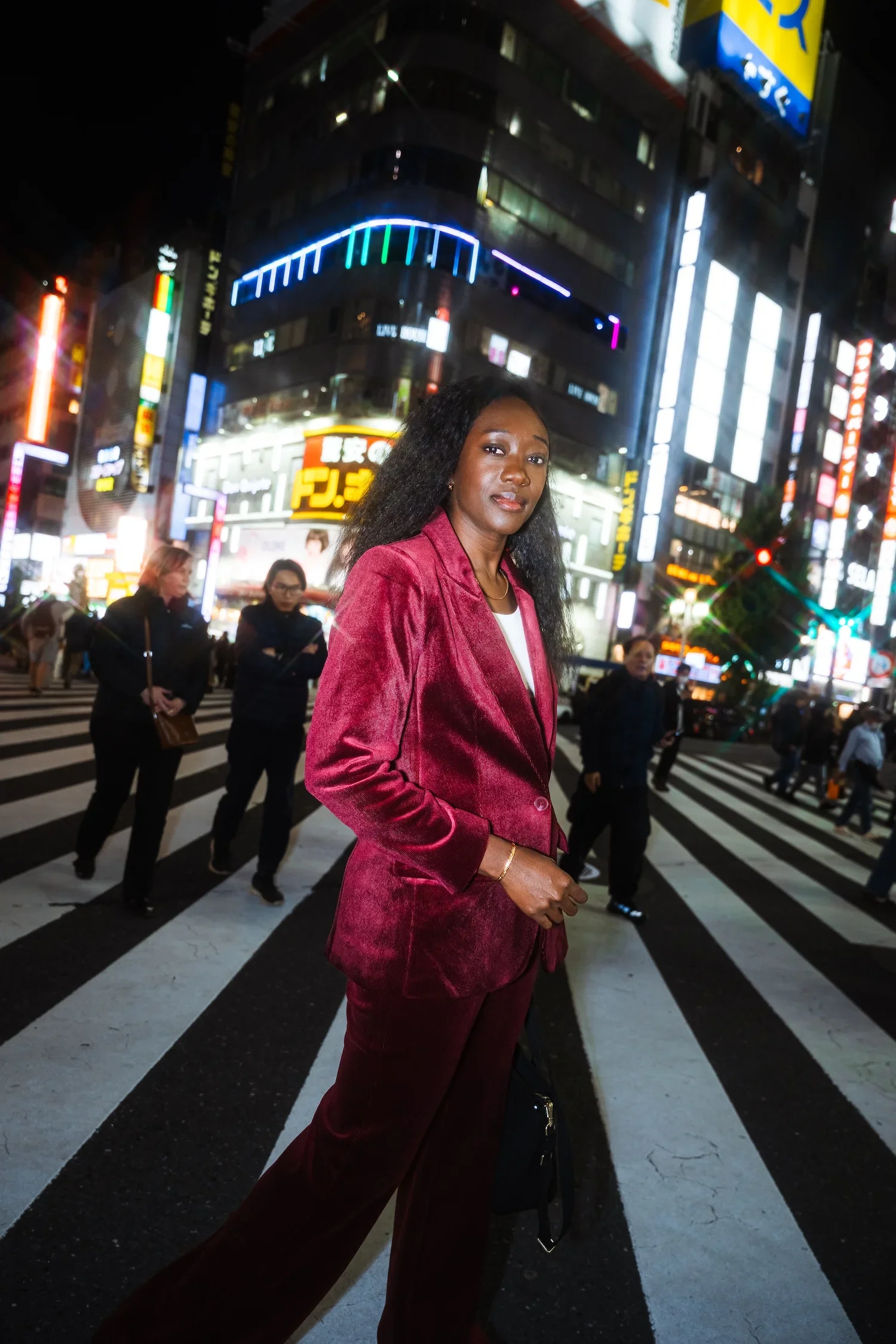 Woman in a red suit posing at Shibuya Crossing during a Tokyo portrait photoshoot