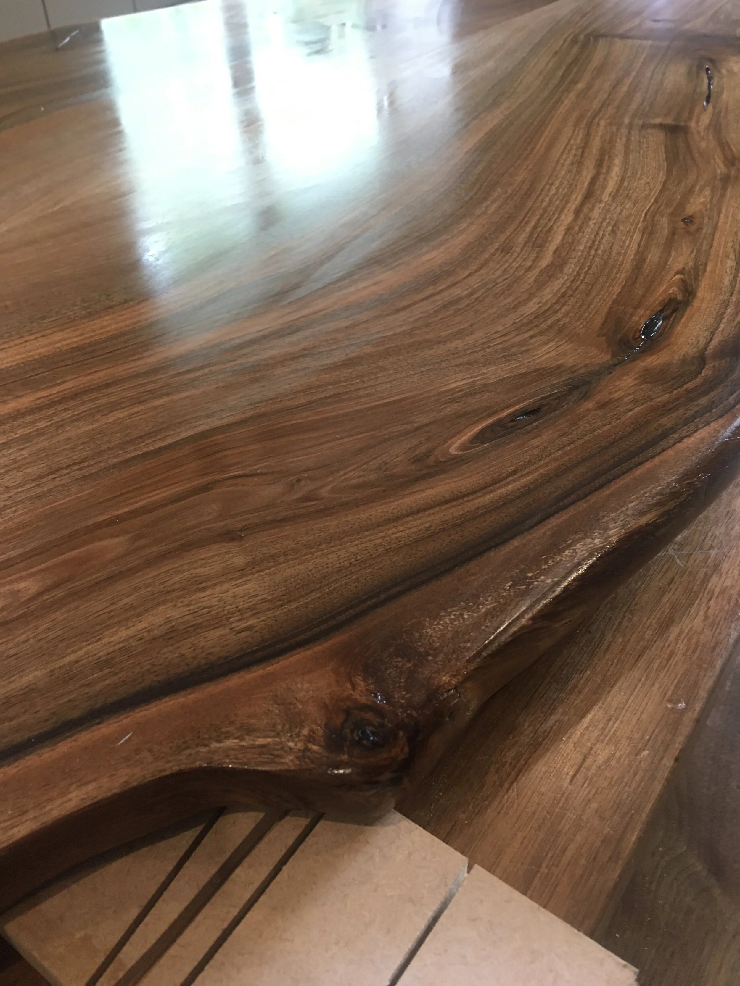 Close-up of a polished wooden table with natural wood grain, knots, and a live edge.