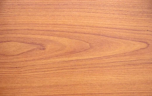 Close-up of a wood surface with a light brown finish and visible grain patterns.