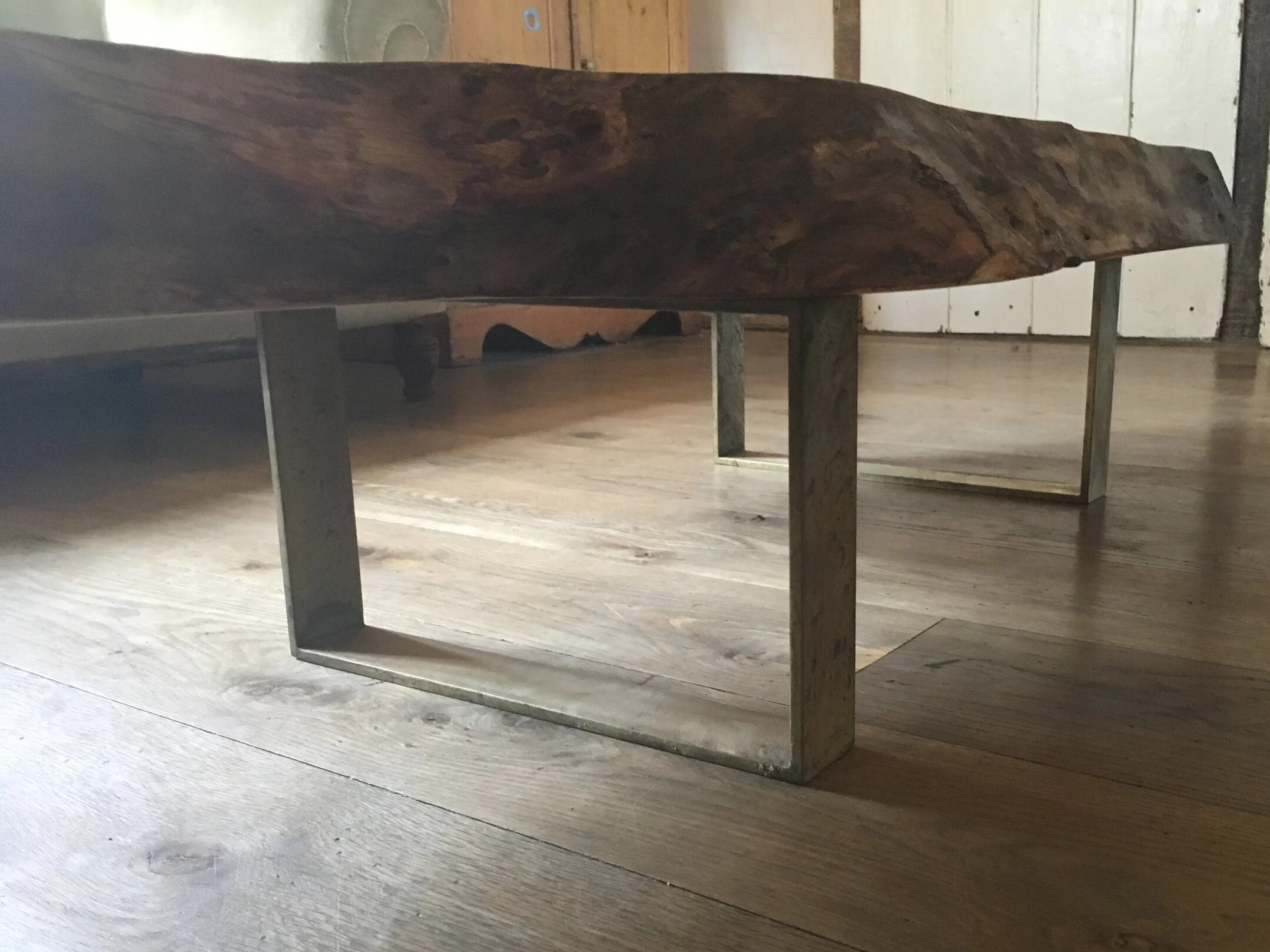 Close-up of a rustic wooden bench with metal legs on a wooden floor in a rustic room.