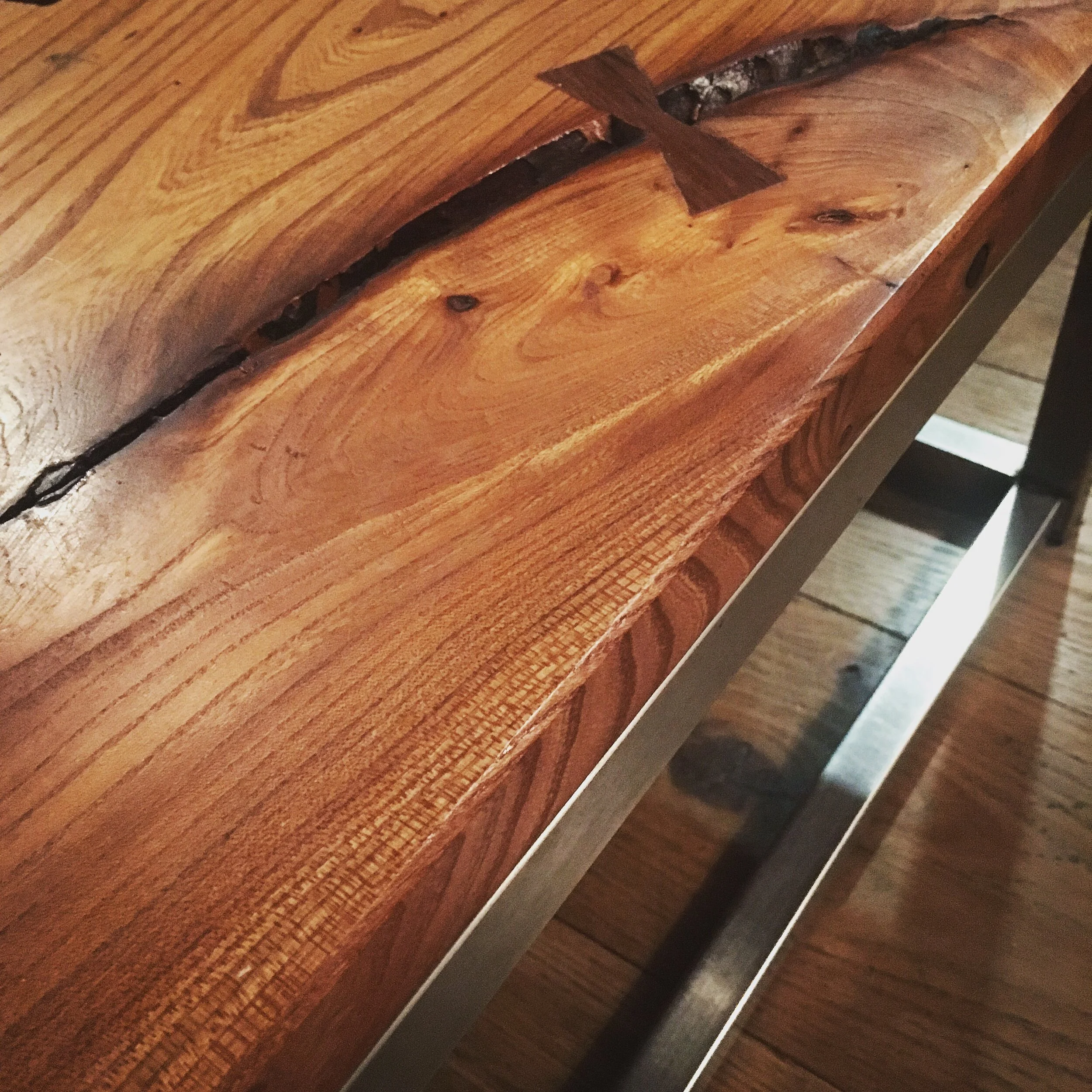 Close-up of a wooden surface with natural grain and a visible crack, reinforced with a piece of tape.