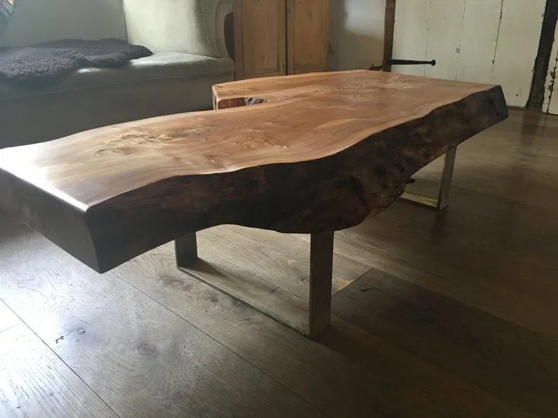A live-edge wooden coffee table with metal legs in a rustic living room.