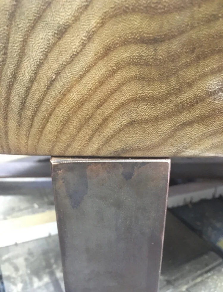 Close-up of a wooden surface with a metal support underneath, showing rust and wear.