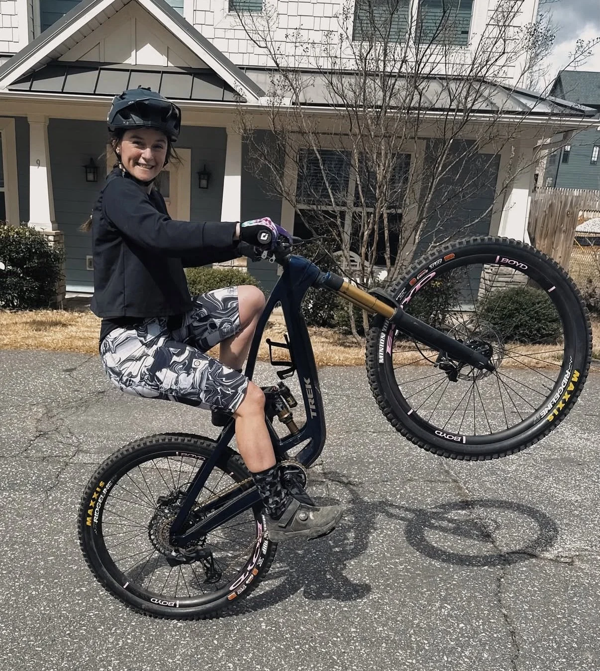 MTB Skills Factory Coach Lilly Driver demos a wheelie while smiling at the camera