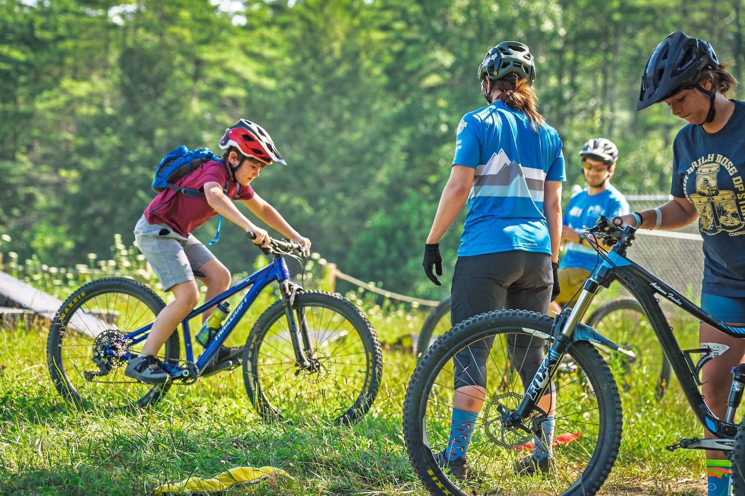young rider is being coaches by a coach on how to ride his mountain bike safely