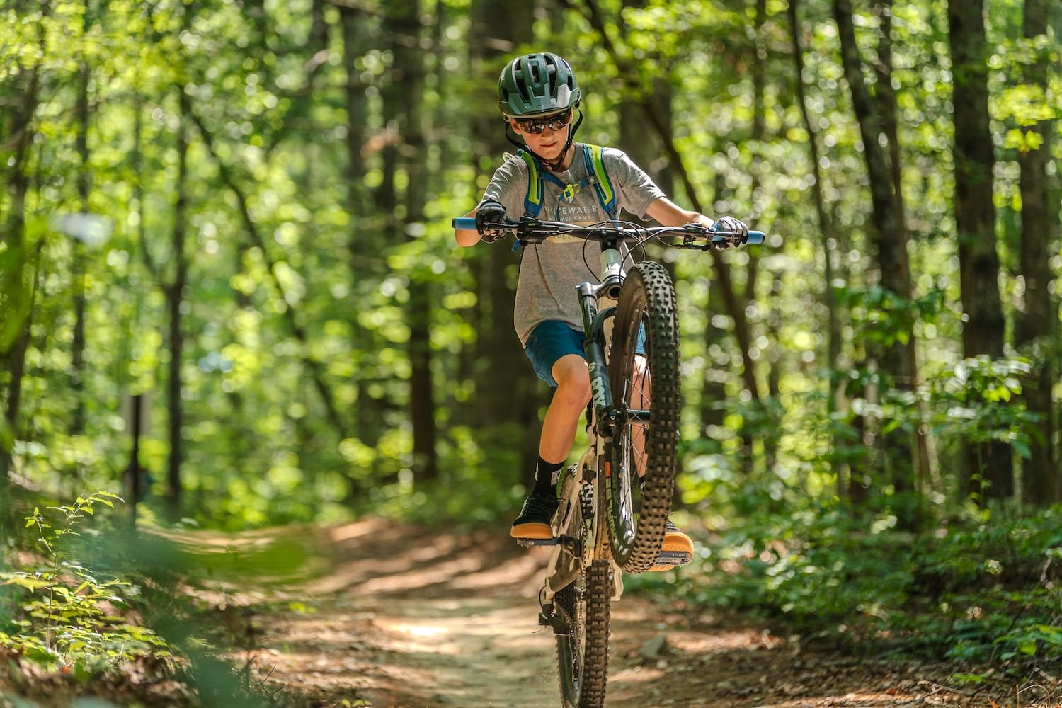 Teen boy doing a wheelie on a wooded trail in DuPont State Forest