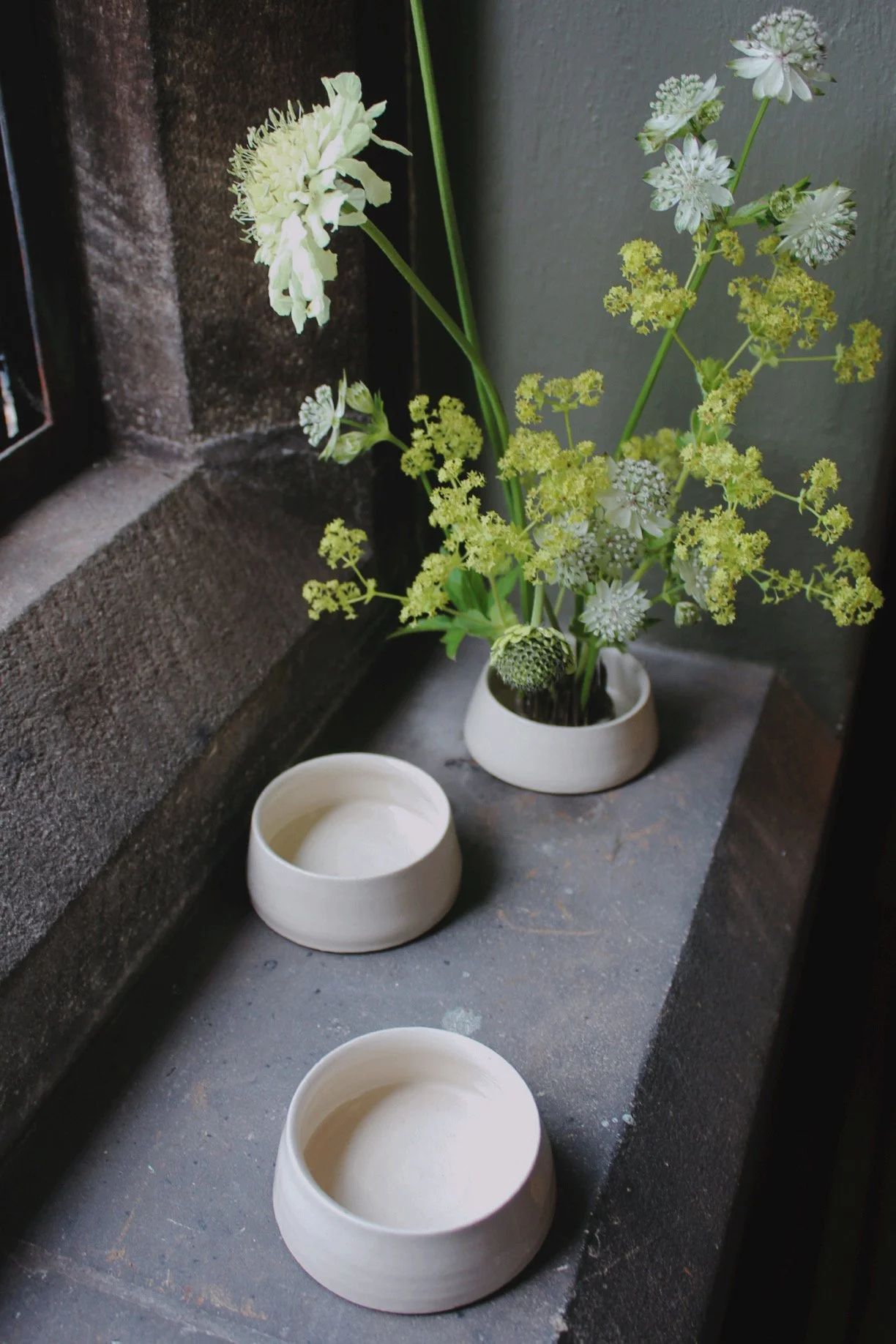 Oatmeal ceramic Kenzan bud bowl holding a small seasonal flower arrangement.