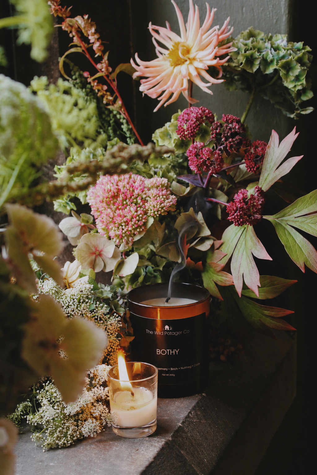 Bothy candle by The Wild Potager Co., photographed with seasonal autumn flowers, foliage and seed heads, capturing the warm, earthy character of the candle and its place within the autumn garden.