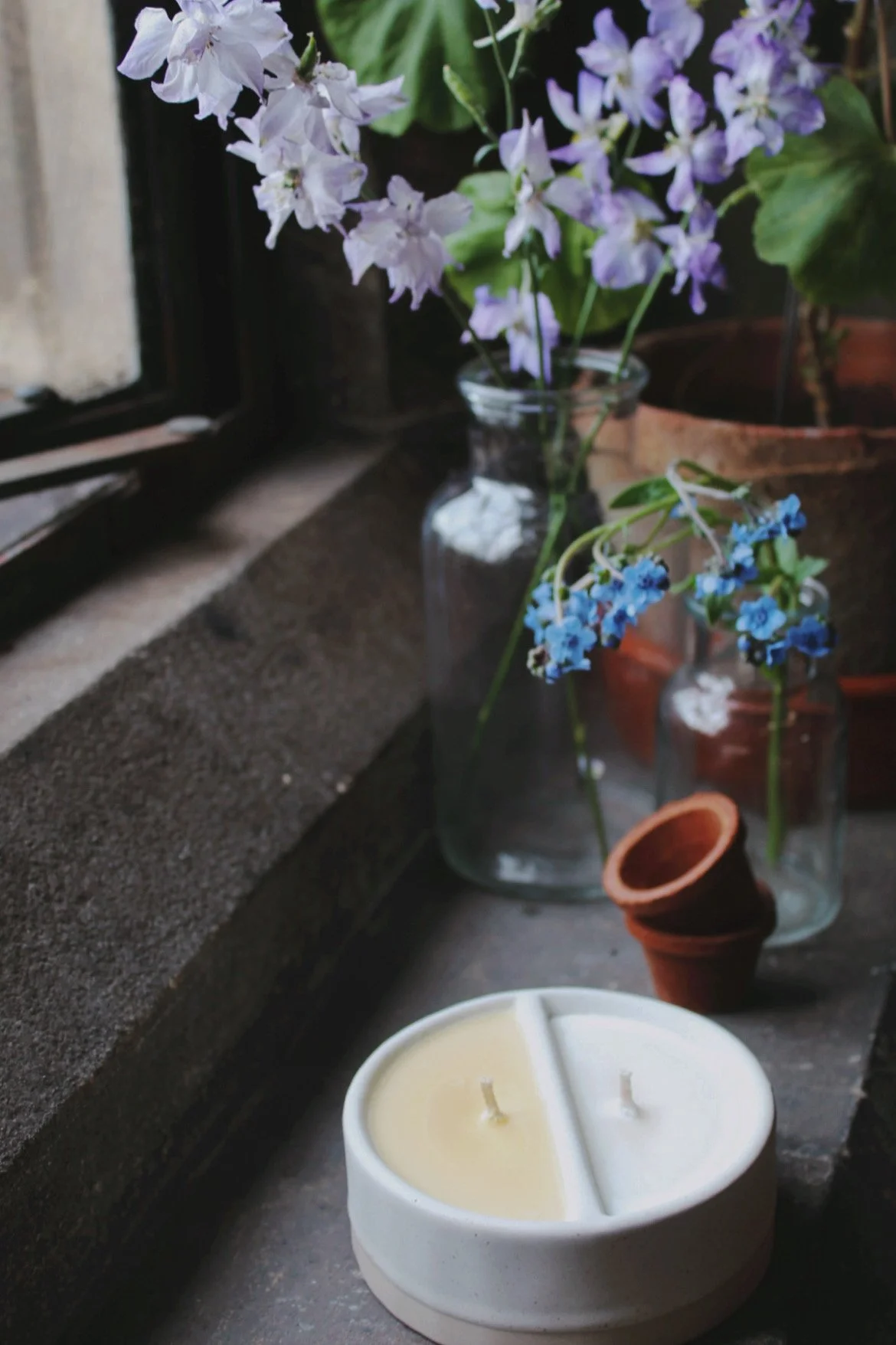 White ceramic double wick candle with terracotta pots and blue flowers