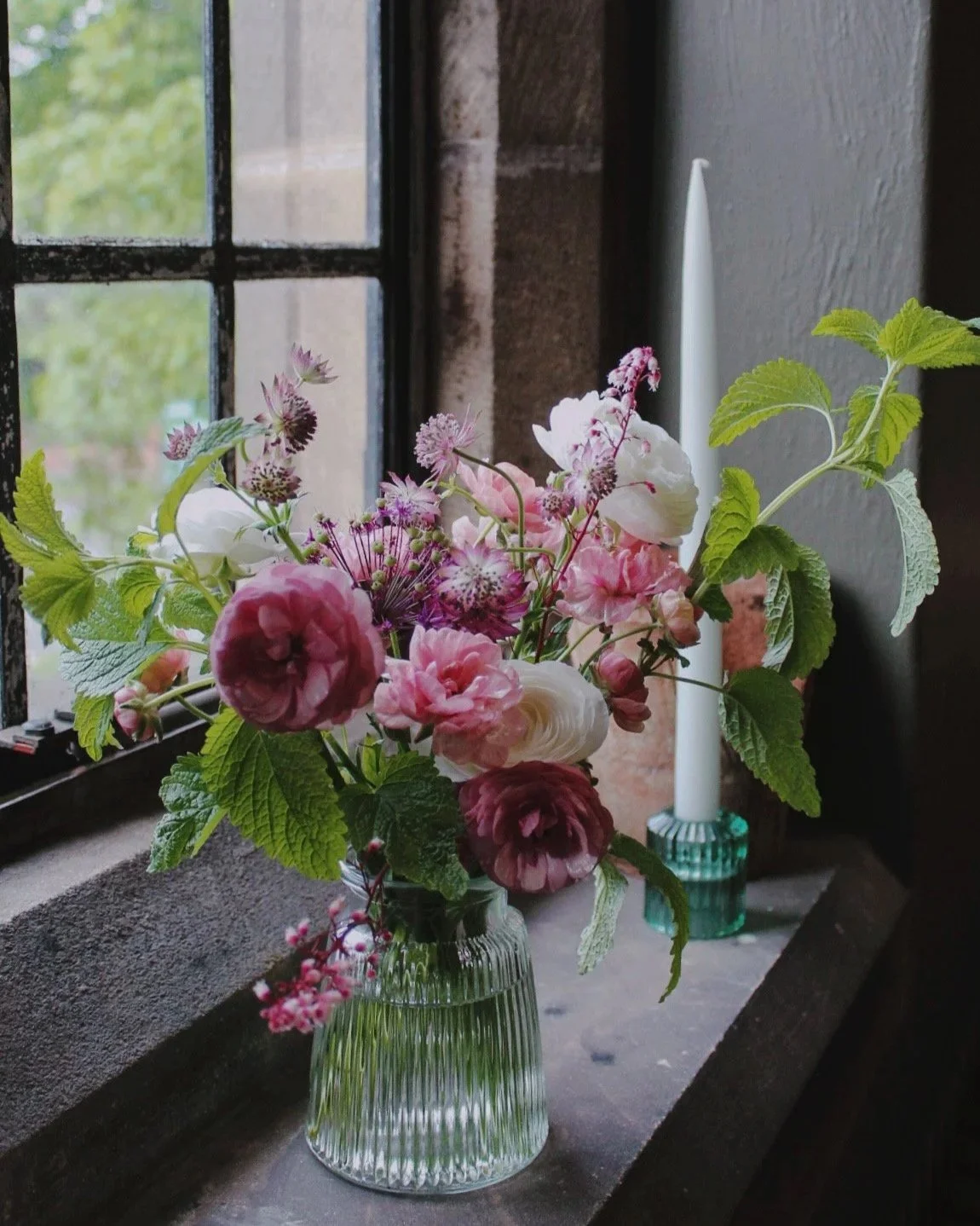 Signature cocktail vase filled with abundant seasonal flowers, soft pinks, fresh foliage and natural trailing stems.