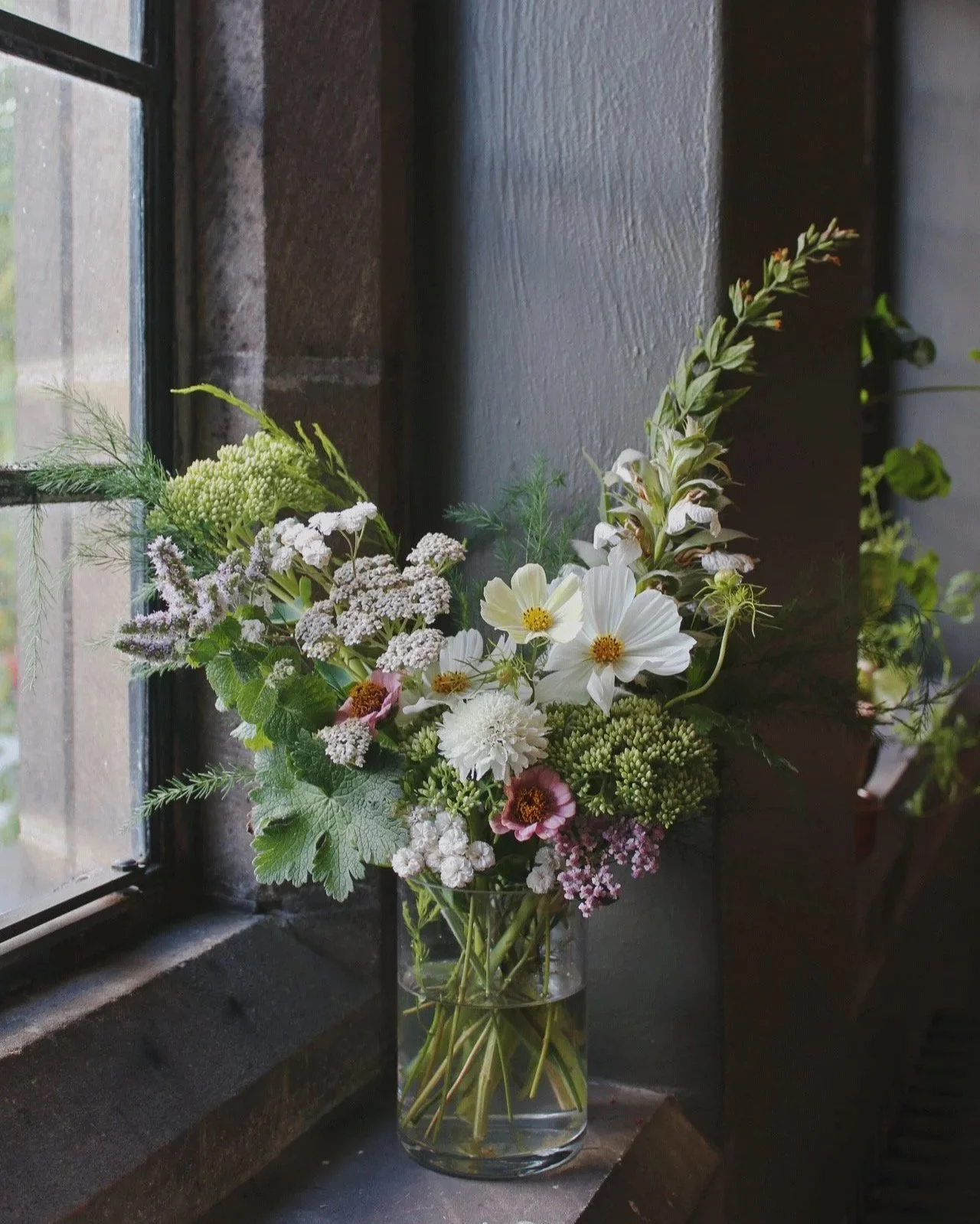 Edit cocktail vase arranged with white seasonal flowers, delicate flowering stems, fresh foliage and natural greenery.