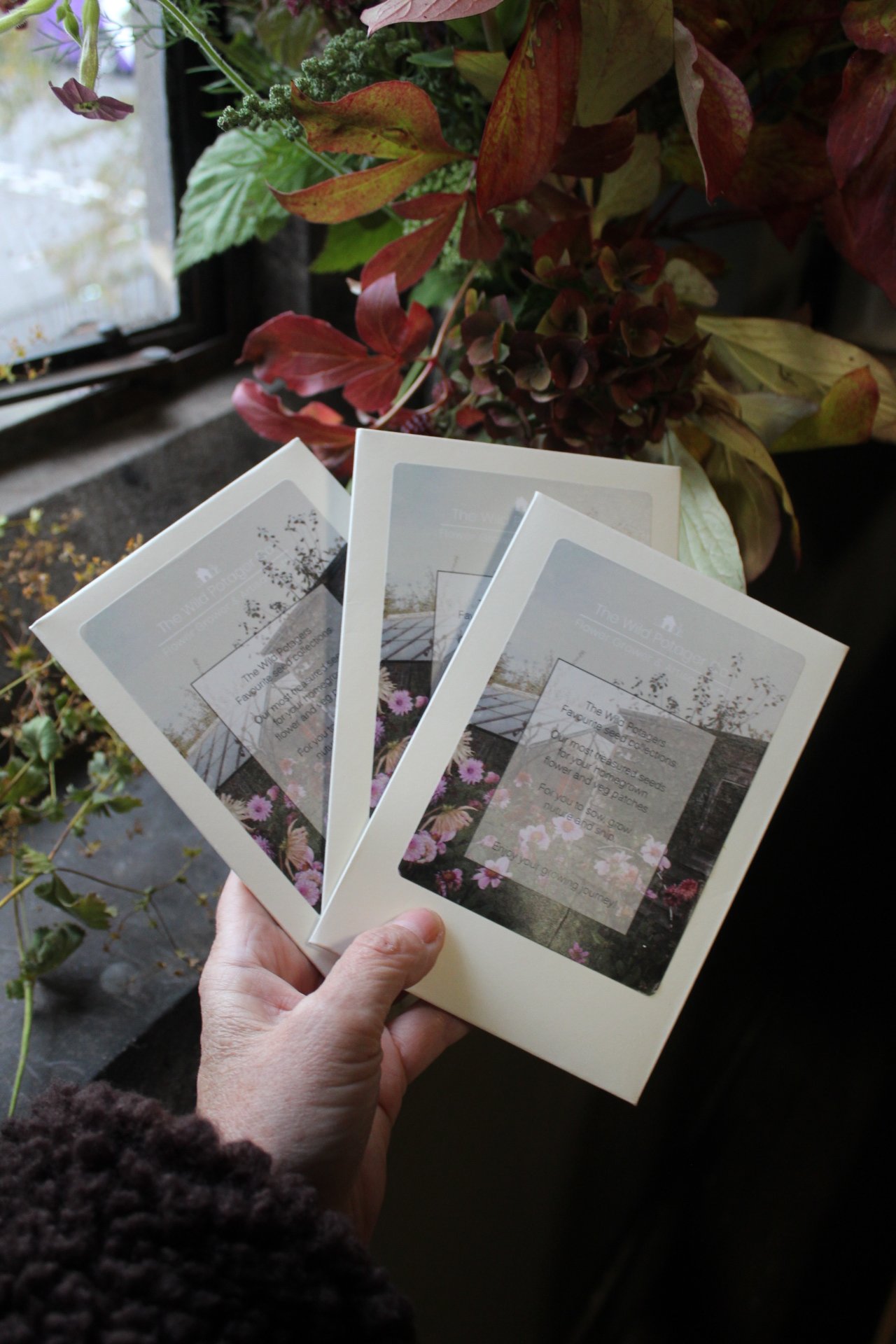A Handful of Sweet Peas from The Wild Potager Co., with four selected sweet pea seed packets photographed alongside seasonal flowers and garden pickings in the studio.
