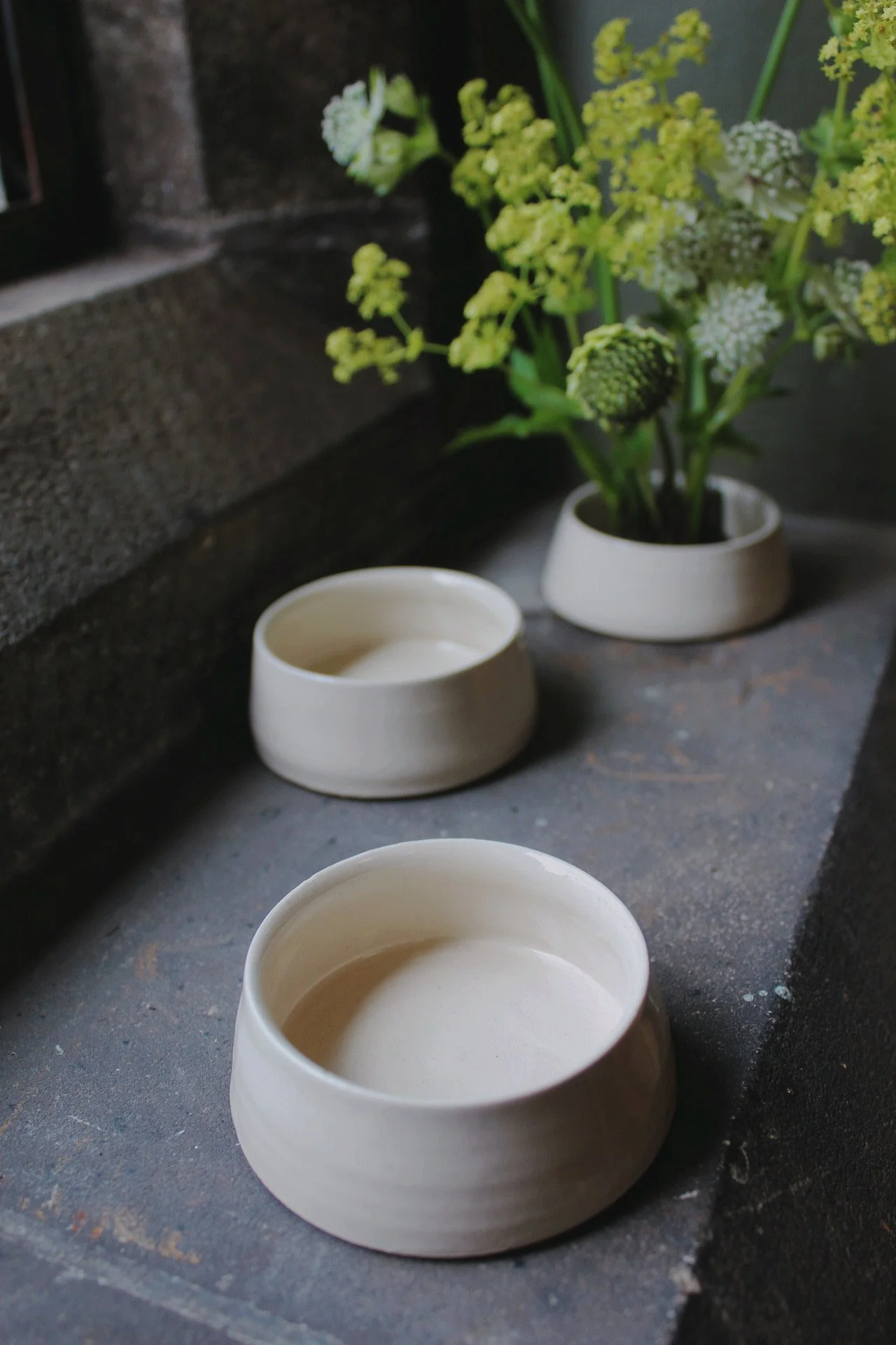 Oatmeal ceramic Kenzan bud bowl holding a small seasonal flower arrangement.