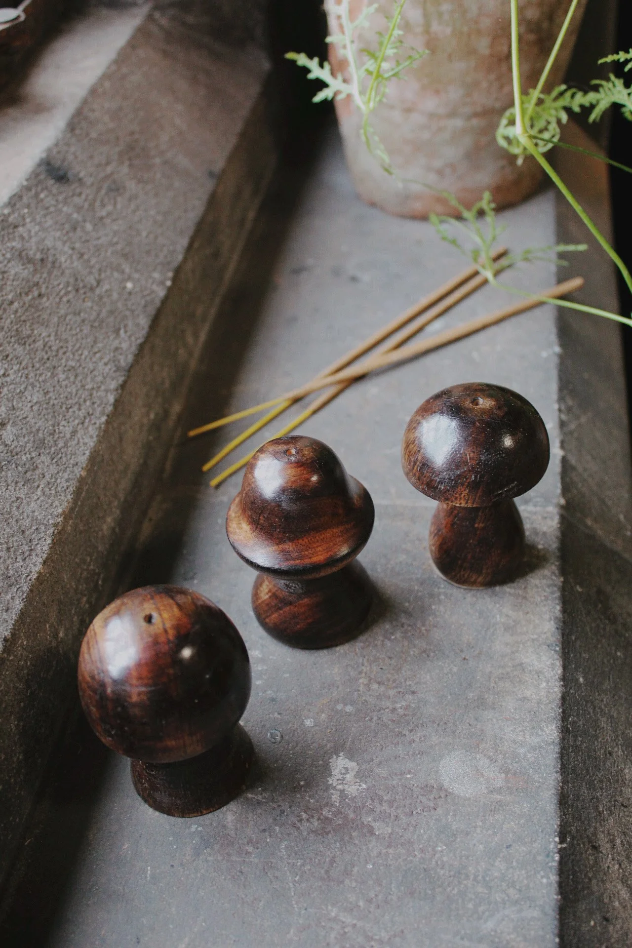 wooden mushroom incense holder in Bell, Classic and Round variations, displayed with incense sticks and green foliage.