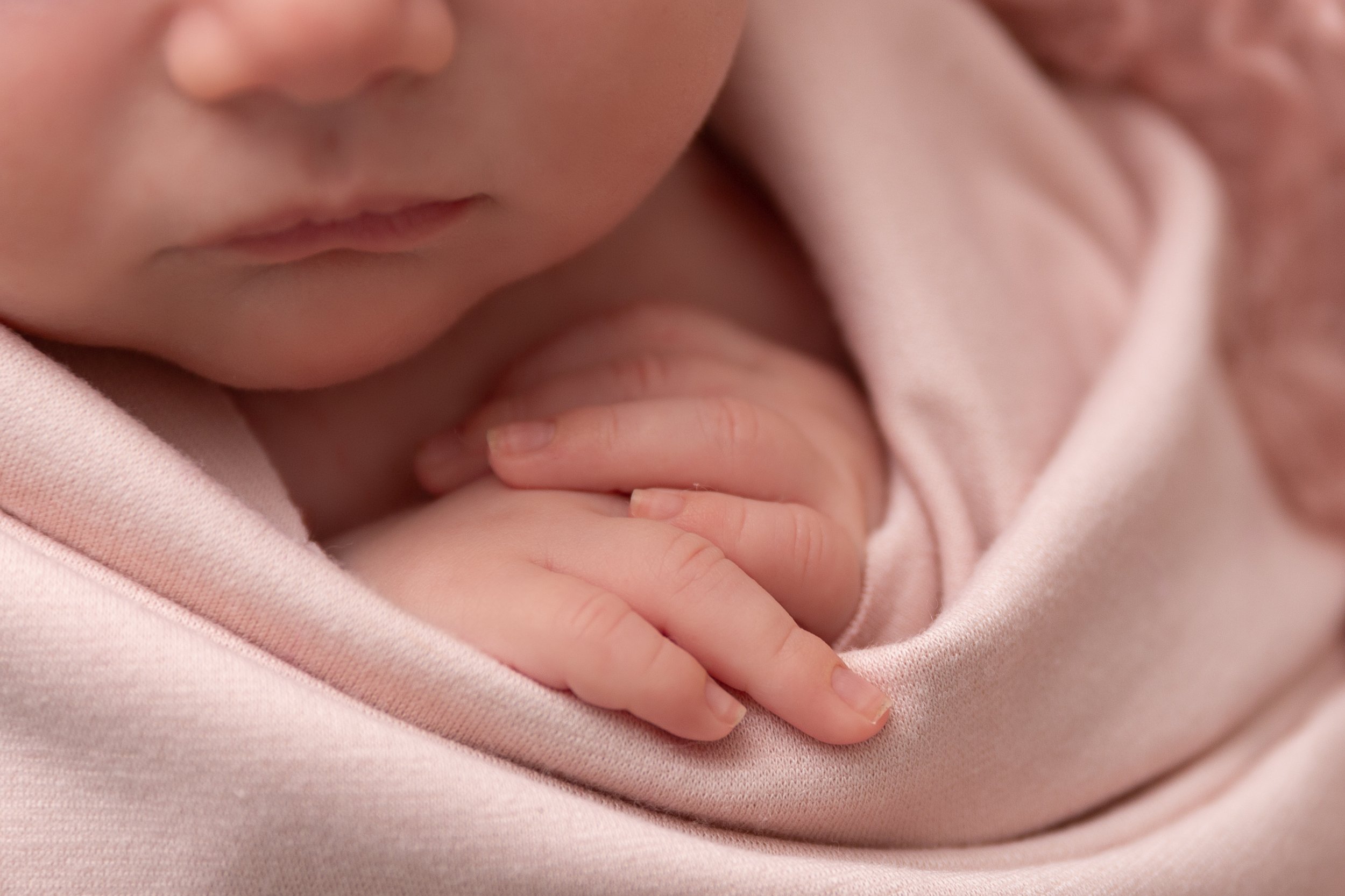 closeup of pink swaddled newborn baby girl's fingers