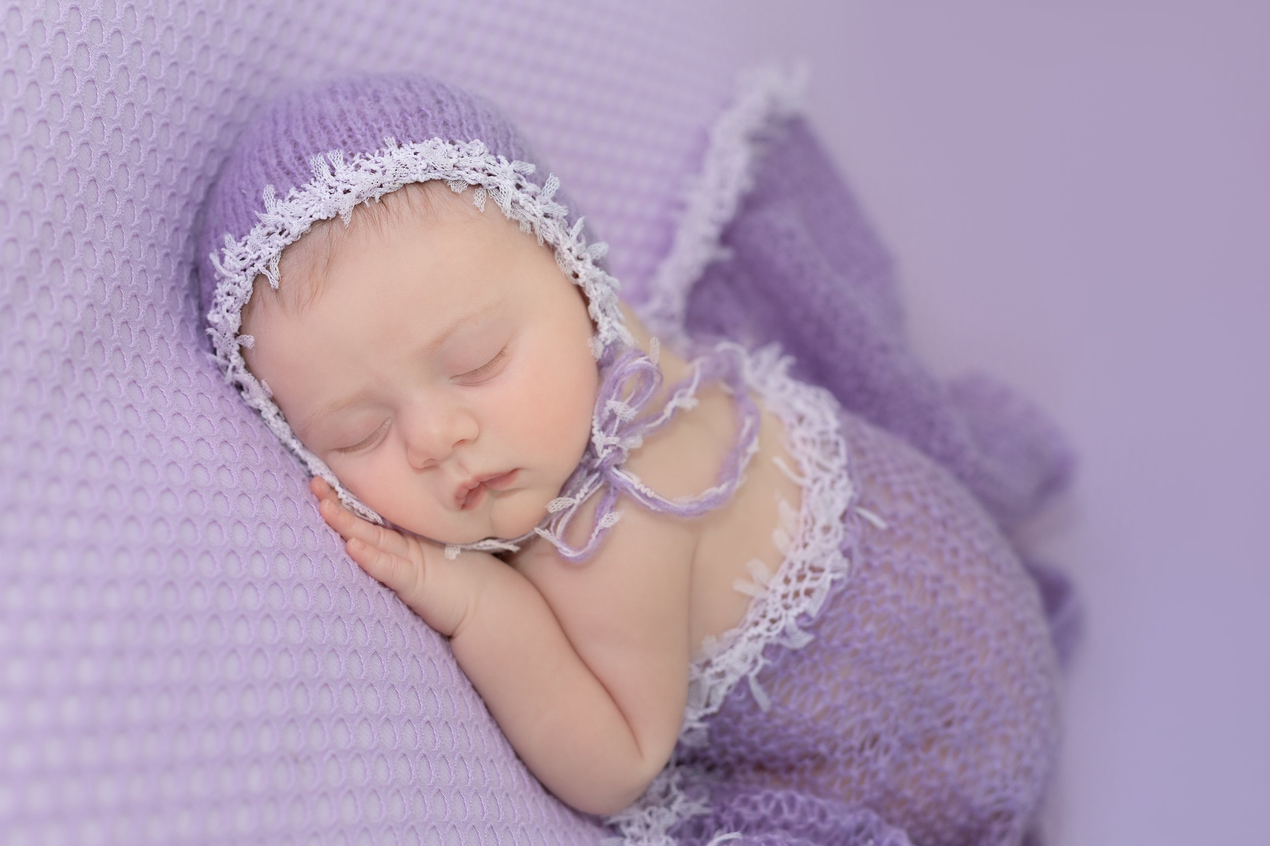 sleeping newborn in purple bonnet