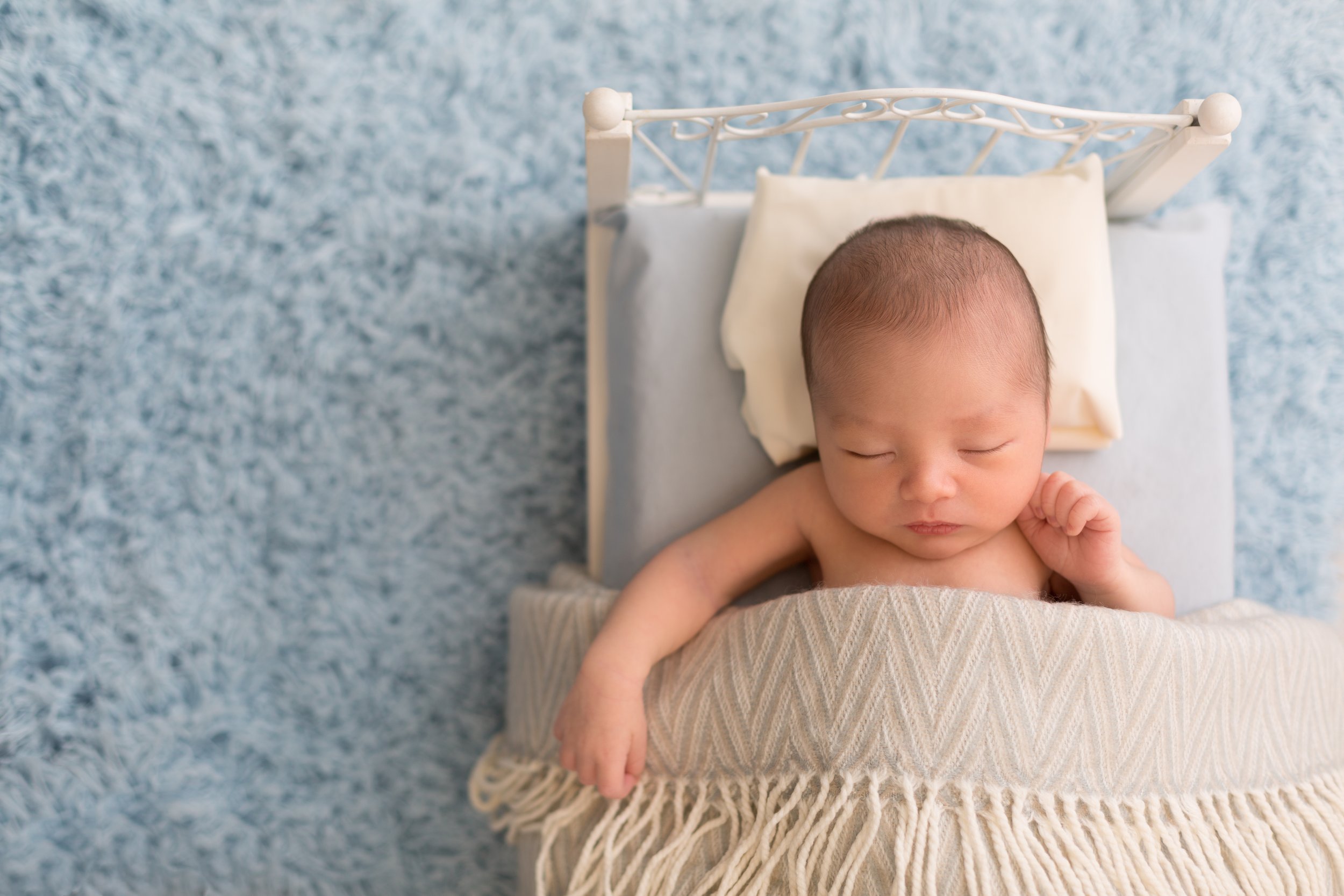 newborn portrait of baby boy sleeping on bed prop